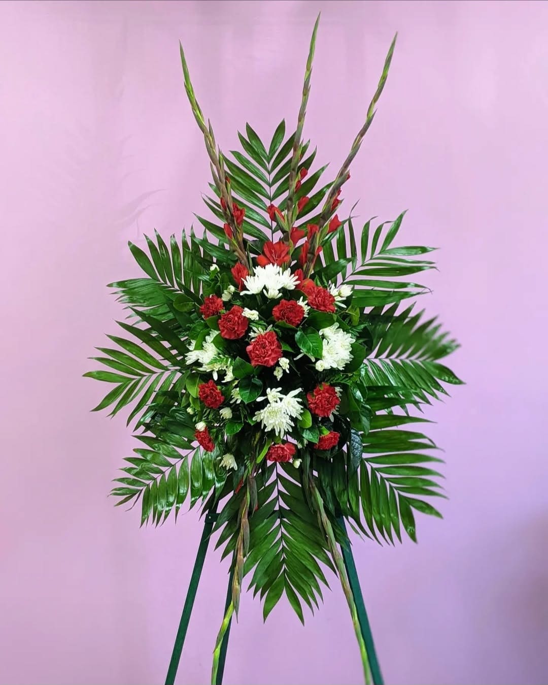 Red standing spray - Standing spray includes red carnations, red gladiolus, white cushion, and emerald. 