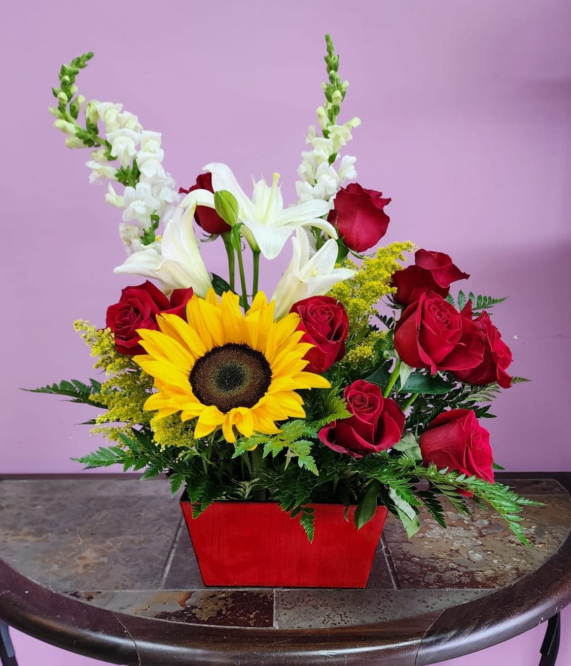 Floral bliss - Arrangement comes with red roses, white lilies, sunflower in a red container. 