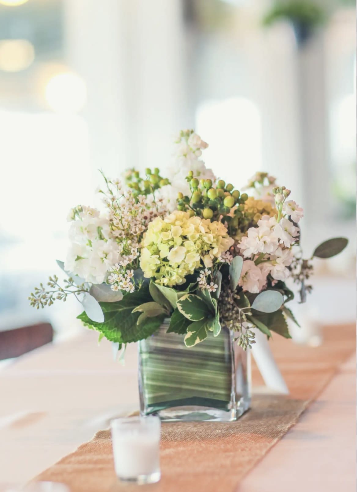 Pastel centerpiece in cube Pastel centerpiece in cube - green hydrangea, white stock , green hypericum, pink wax flower, eucalyptus, greens in 5X5 glass cube with liner