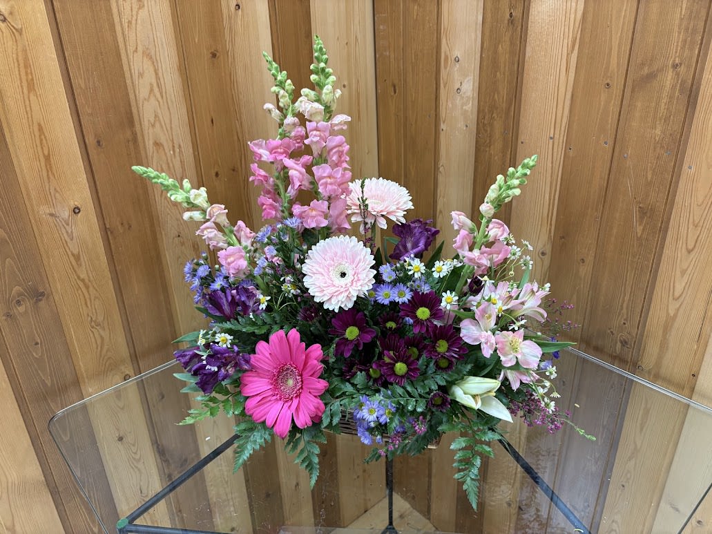 Country Blooms - Take a walk through a country meadow with this fresh flower basket! Pretty blooms of pink and purple nestle happily inside a natural gift basket as playful purple butterflies flutter overhead. Fresh flowers including snapdragons, alstroemeria, mini carnations are assembled in a natural basket with decorative butterflies. Orientation: One-Sided  SUBSTITUTION POLICY – Always deliver the freshest flowers! Please note the bouquet pictured reflects our original design.  If the exact flowers or container in this arrangement are not available, our local florists will create a beautiful bouquet with the freshest available flowers.