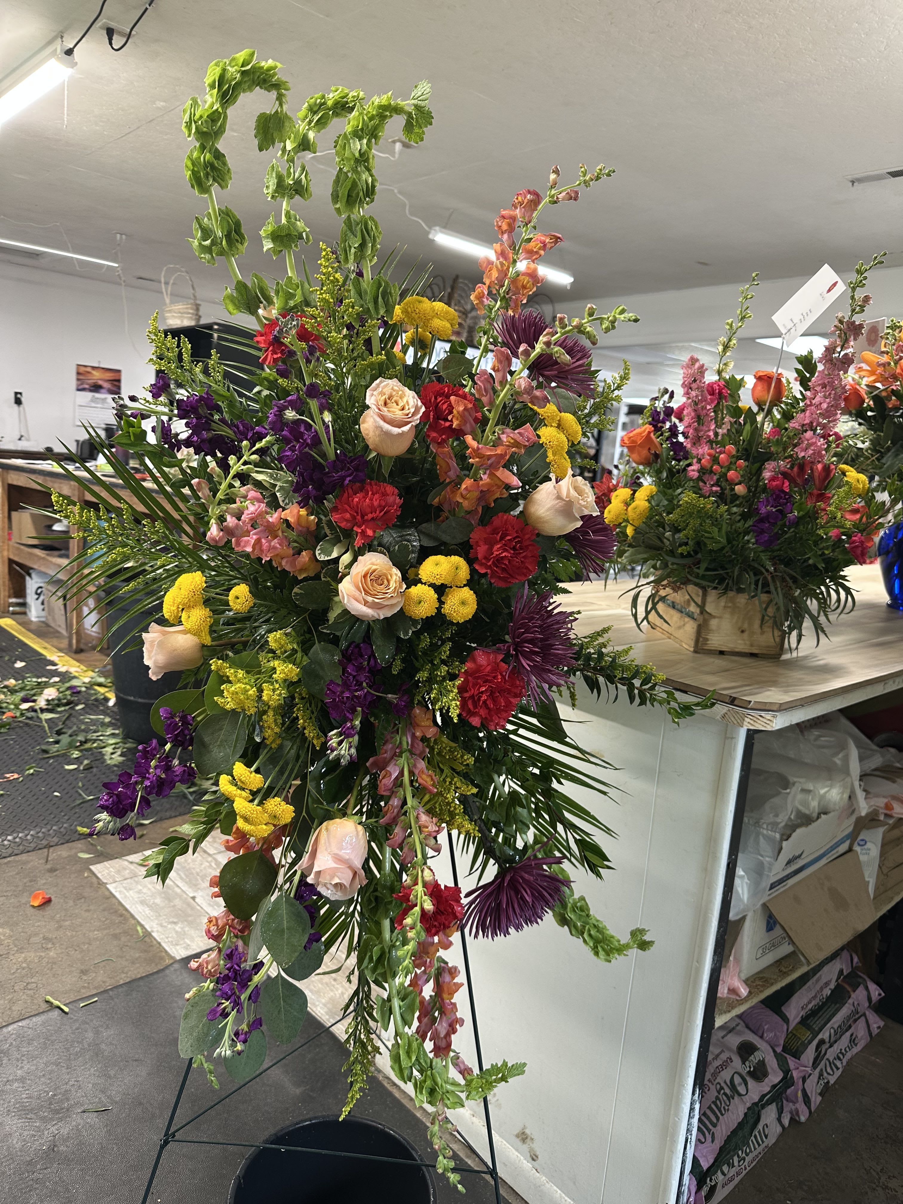 Garden Easel - A beautiful mix of roses, snaps, buttons, bells, carnations, and spider mums, along with several greens.