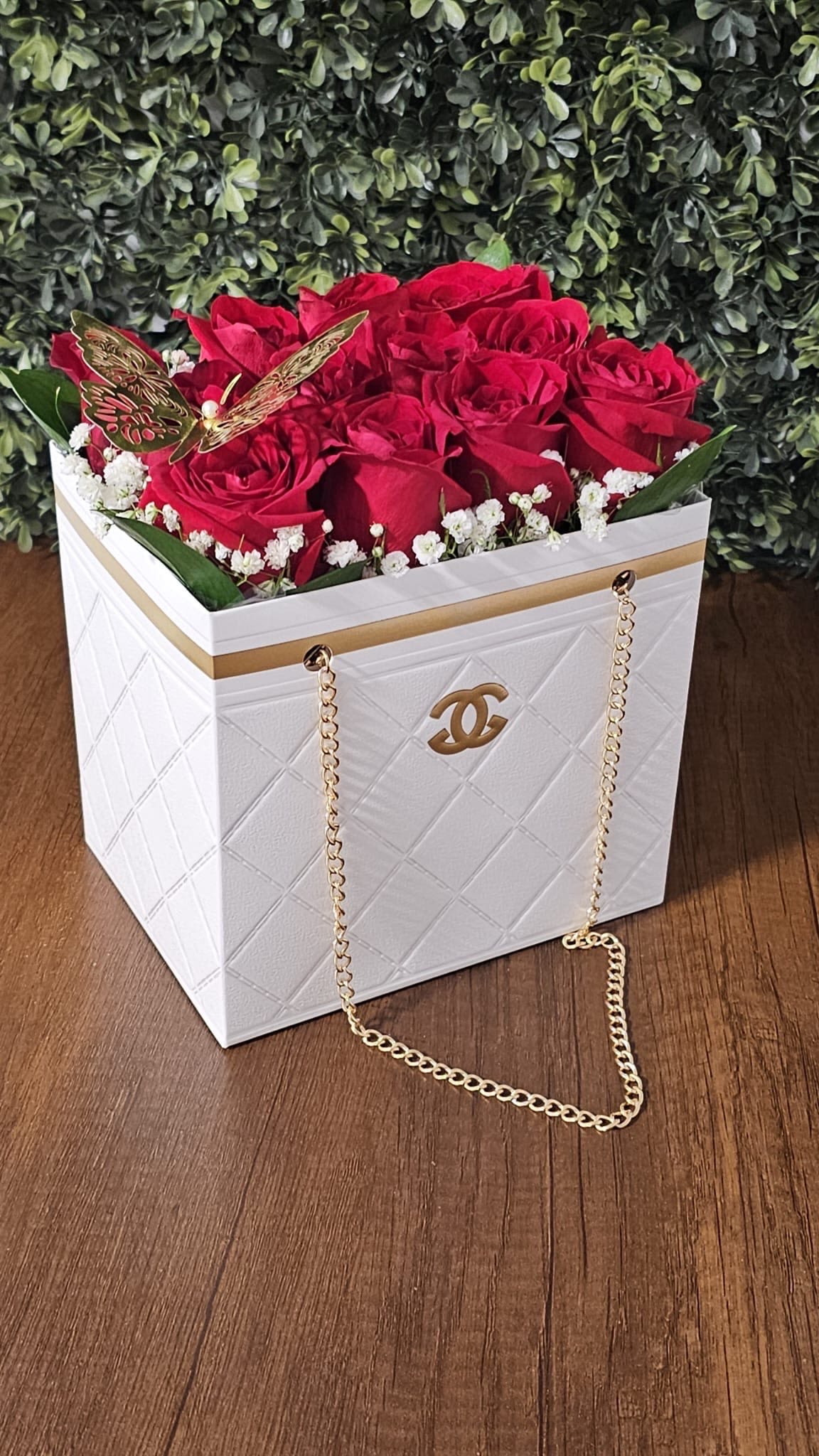 White Chanel Bag - Vibrant roses, delicate baby's breath, lush greenery, and a gold butterfly accented with a Chanel ribbon.