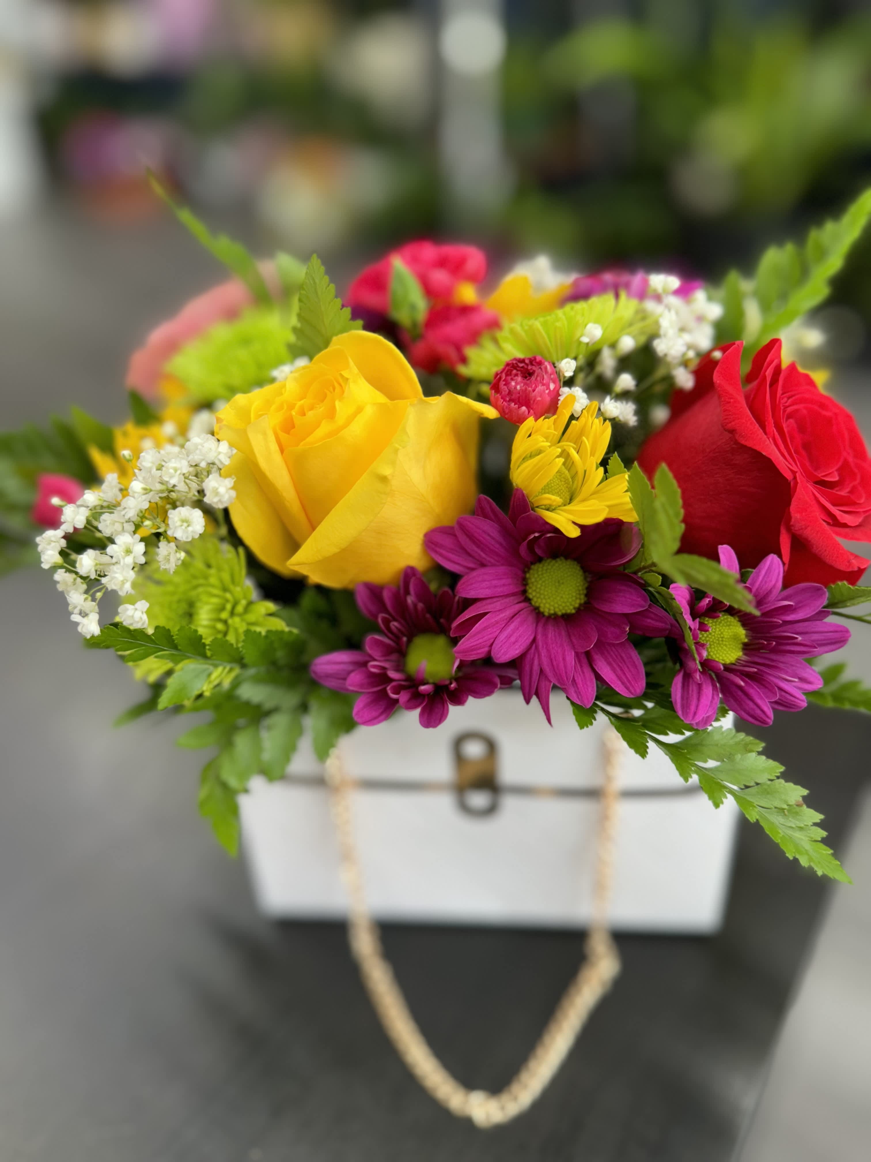 Sunset Radiance Sunset Radiance - "Embrace the vibrant beauty of 'Sunset Radiance,' a stunning arrangement in a stylish paper bag. Featuring yellow roses, red roses, hot pink mini carnations, purple daisies, and lush greenery, this bouquet is perfect for brightening up any occasion with its radiant colors."