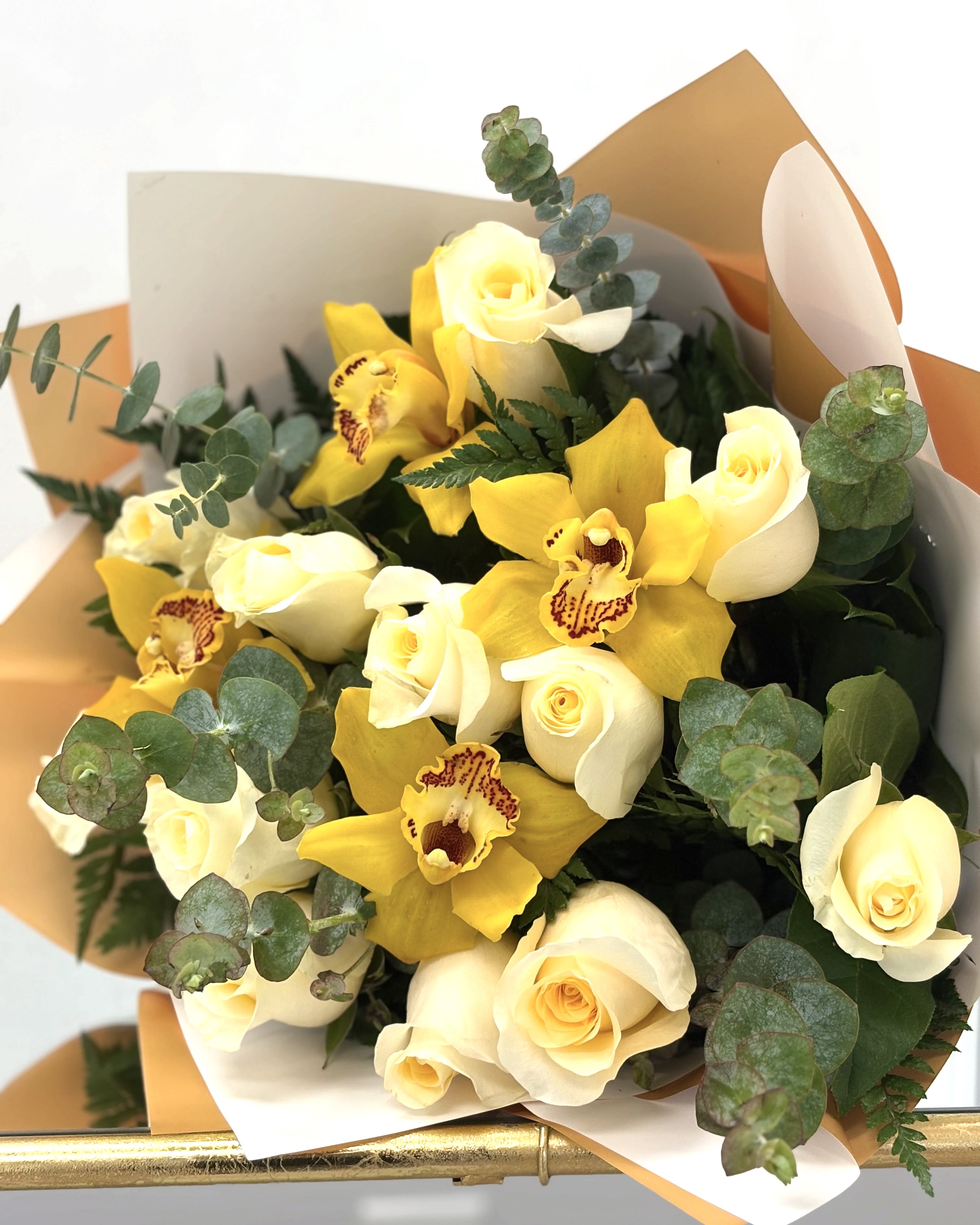 Golden Hour by VLM Flowers  - Like the soft light just before sunset, Golden Hour captures a fleeting moment of radiance and joy. Featuring vivid yellow cymbidium orchids nestled among velvety cream roses and lush greenery, this bouquet brings a sense of sunshine and serenity to any space. It’s a bright embrace—perfect for celebrations, congratulations, or simply to brighten someone’s day.