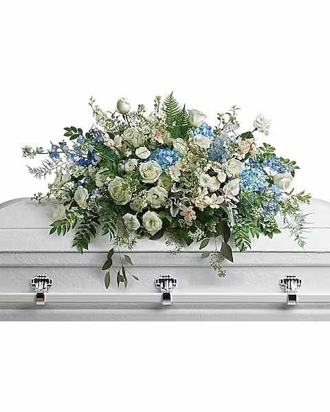 Tender Remembrance Casket Spray - As soft and delicate as a tender remembrance, this stunning spray of sky blue hydrangea and pure white roses brings a fresh, natural beauty to the casket. This stunning spray includes blue hydrangea, white roses, white spray roses, white alstroemeria, white lisianthus, blue delphinium, white larkspur, white stock, white waxflower, dusty miller, huckleberry, asparagus plumosus, pitta negra, lily grass, dagger fern, and lemon leaf.  