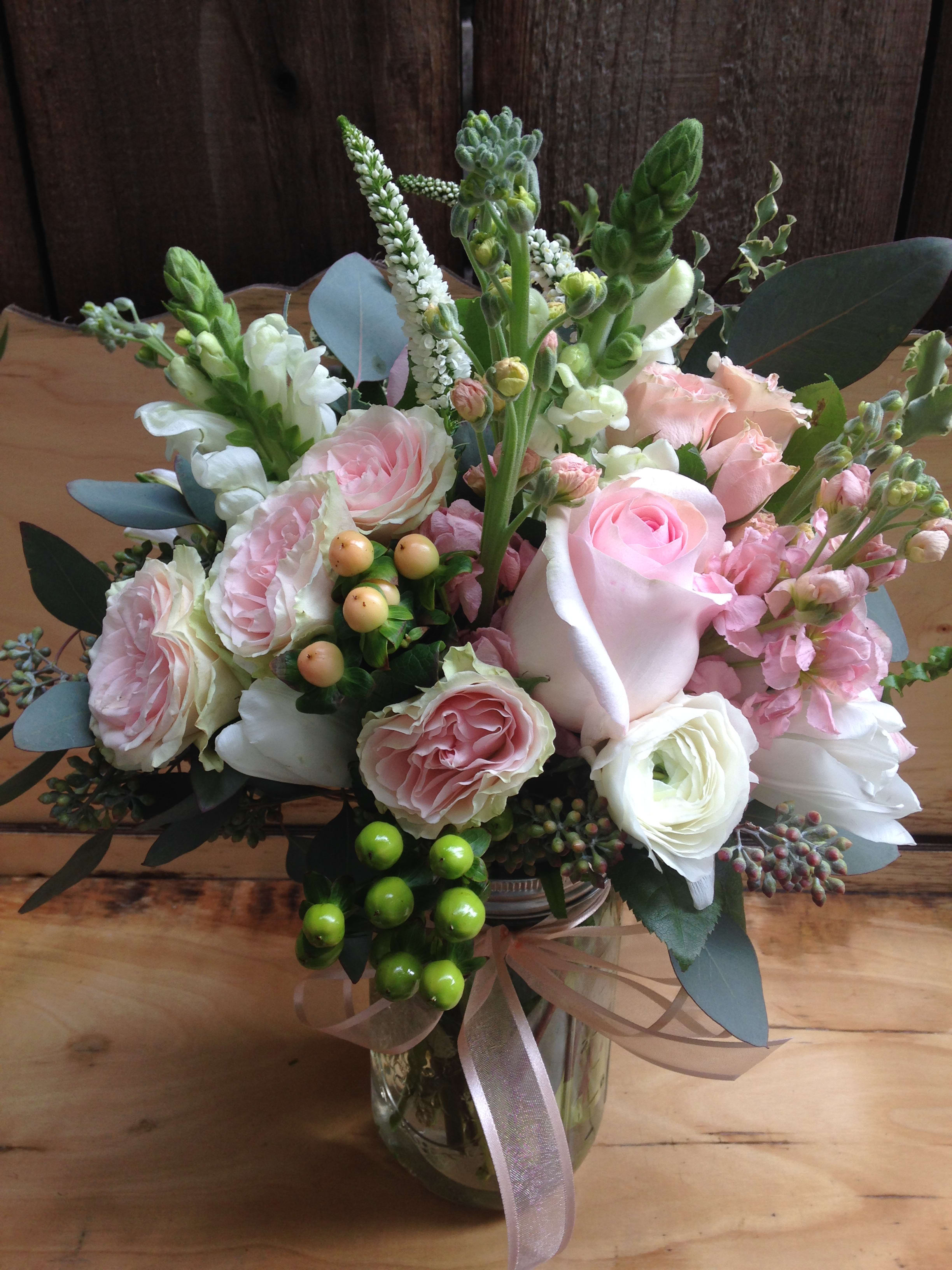 Sweet Love Jar Sweet Love Jar - A sweet and lovely arrangement of pale pink roses, snap dragon spray roses, stock, hypericum berries and more, It comes with a pale pink ribbon wrapped around a rustic mason jar. (Some flowers may be subject to change depending on the season. We will contact you with available flower substitutions; please contact us with specific questions if you are concerned with flower availability, thanks!) Featured Arrangement $125.75