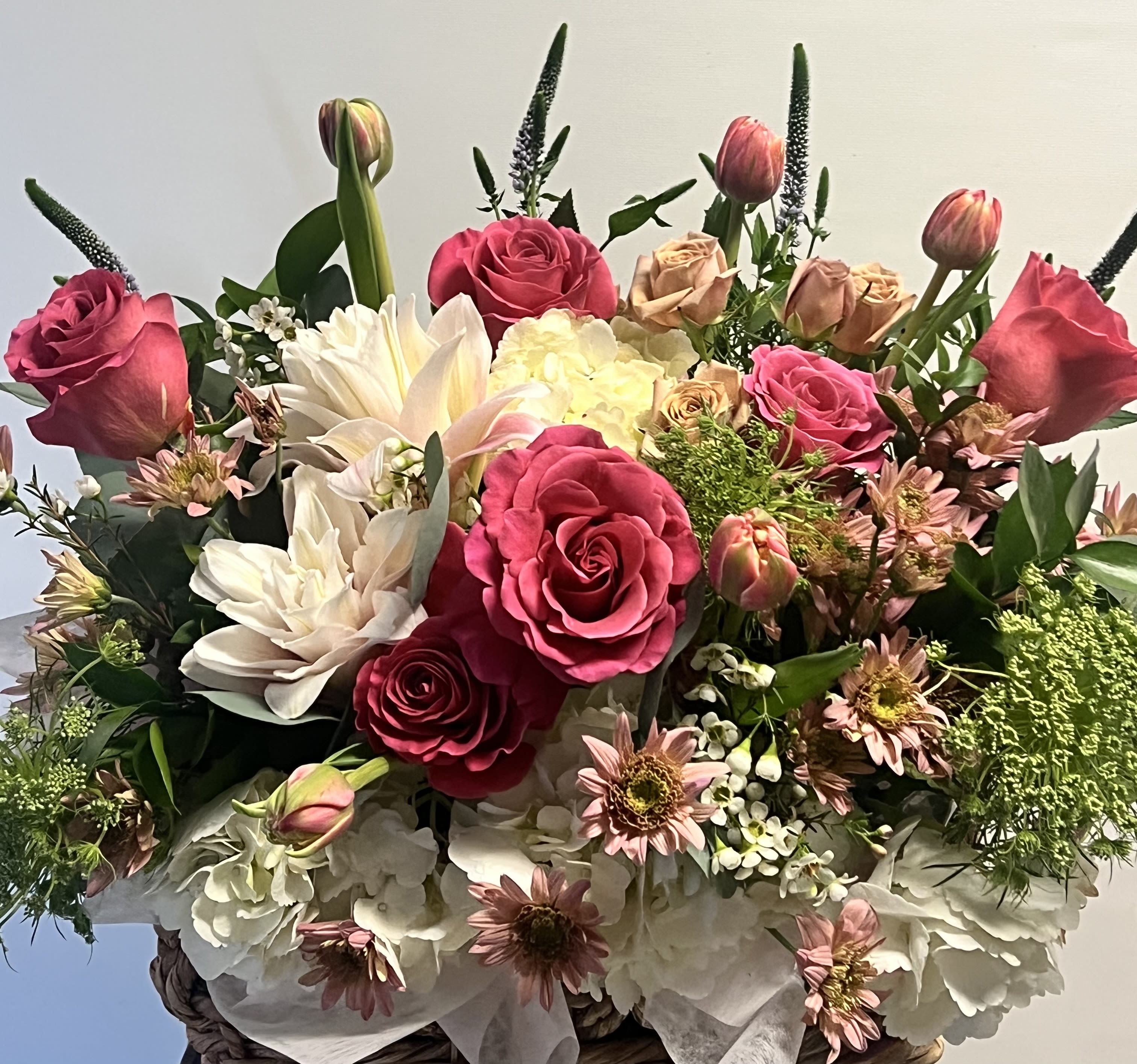 Berry Blush Garden Basket - Bring elegance and romance into any room with our Berry Blush Garden Basket. This lush floral arrangement features a luxurious blend of deep pink roses, soft blush dahlias, creamy white hydrangeas, delicate tulips, and seasonal accent blooms. Expertly arranged in a natural woven basket, this design is perfect for birthdays, anniversaries, or just to show someone special how much you care. The rich textures and sophisticated color palette make it a stunning and heartfelt gift.  Substitution Note: Substitutions may be made based on seasonal or in-store availability. The arrangement will be delivered as similar as possible