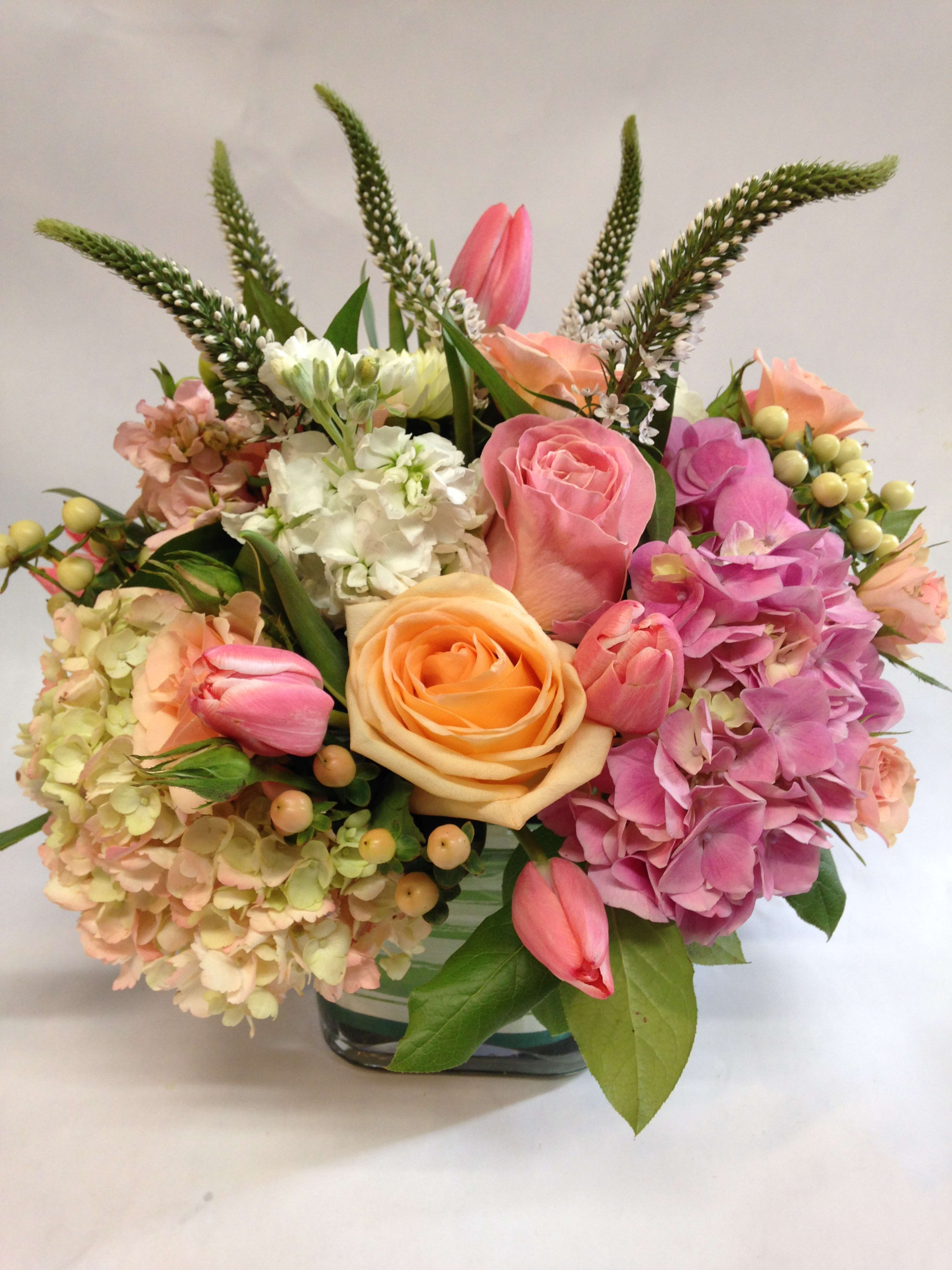 Pink and pretty. Pink and pretty. - This low centerpiece is complete with peach roses, tulips, snap dragon, stock, hydrangeas, hypericum, spray roses and various greenery. (Some flowers may be subject to change depending on the season. We will contact you with available flower substitutions; please contact us with specific questions if you are concerned with flower availability, thanks!) Featured arrangement: $135.75 [Regular Price)
