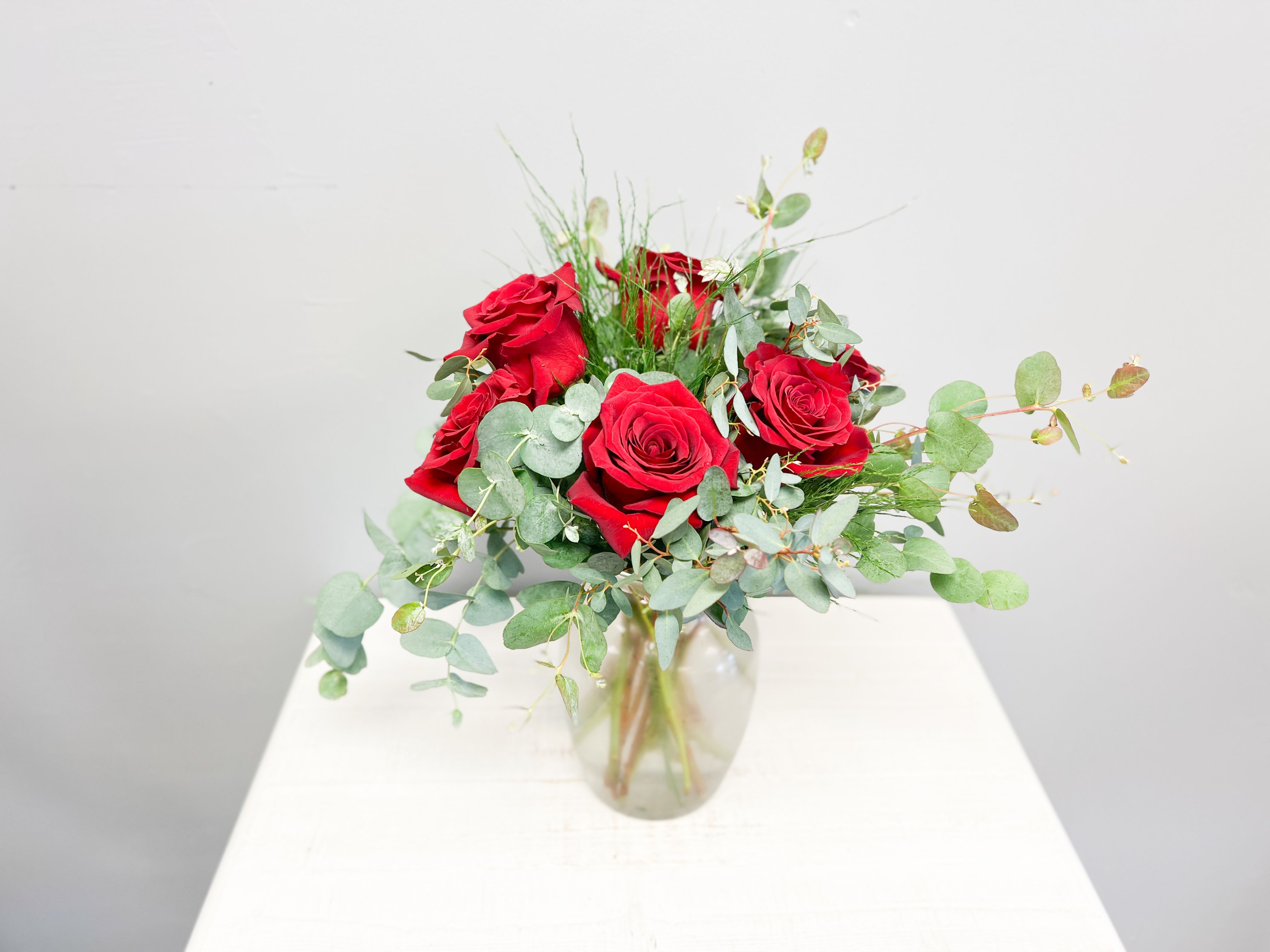 Simply Romantic - Let your love speak for itself with our Simply Romantic arrangement. This timeless design features lush red roses accented with soft eucalyptus and airy greenery, arranged in a clear glass vase. Elegant and understated, it’s the perfect gesture for anniversaries, just because, or any heartfelt moment.  Vase style and greenery may vary based on availability. 