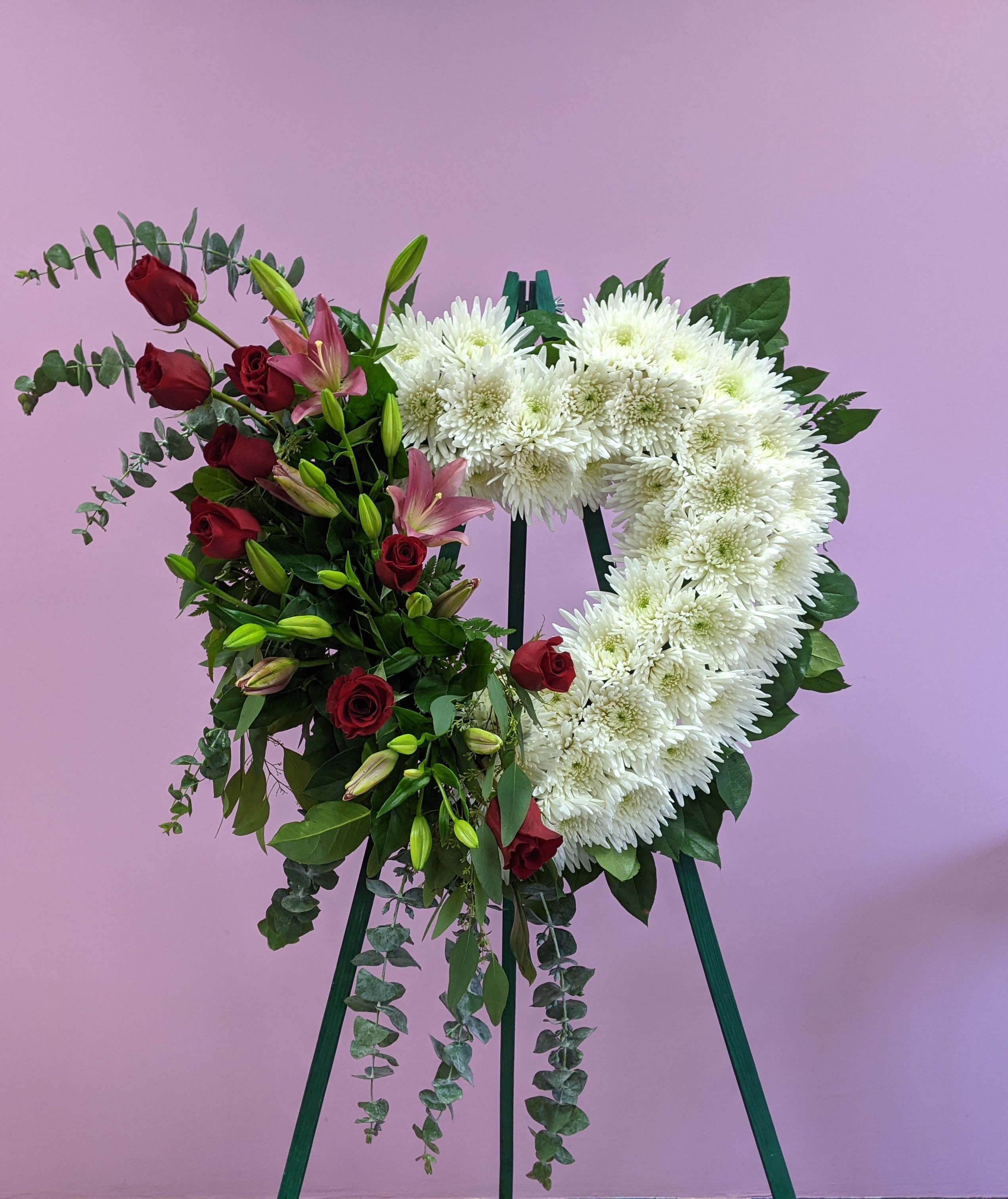 Loving Memory  - Express deepest sympathy through this heart standing spray that includes: Red roses, pink lily's, white mums and greenery. 