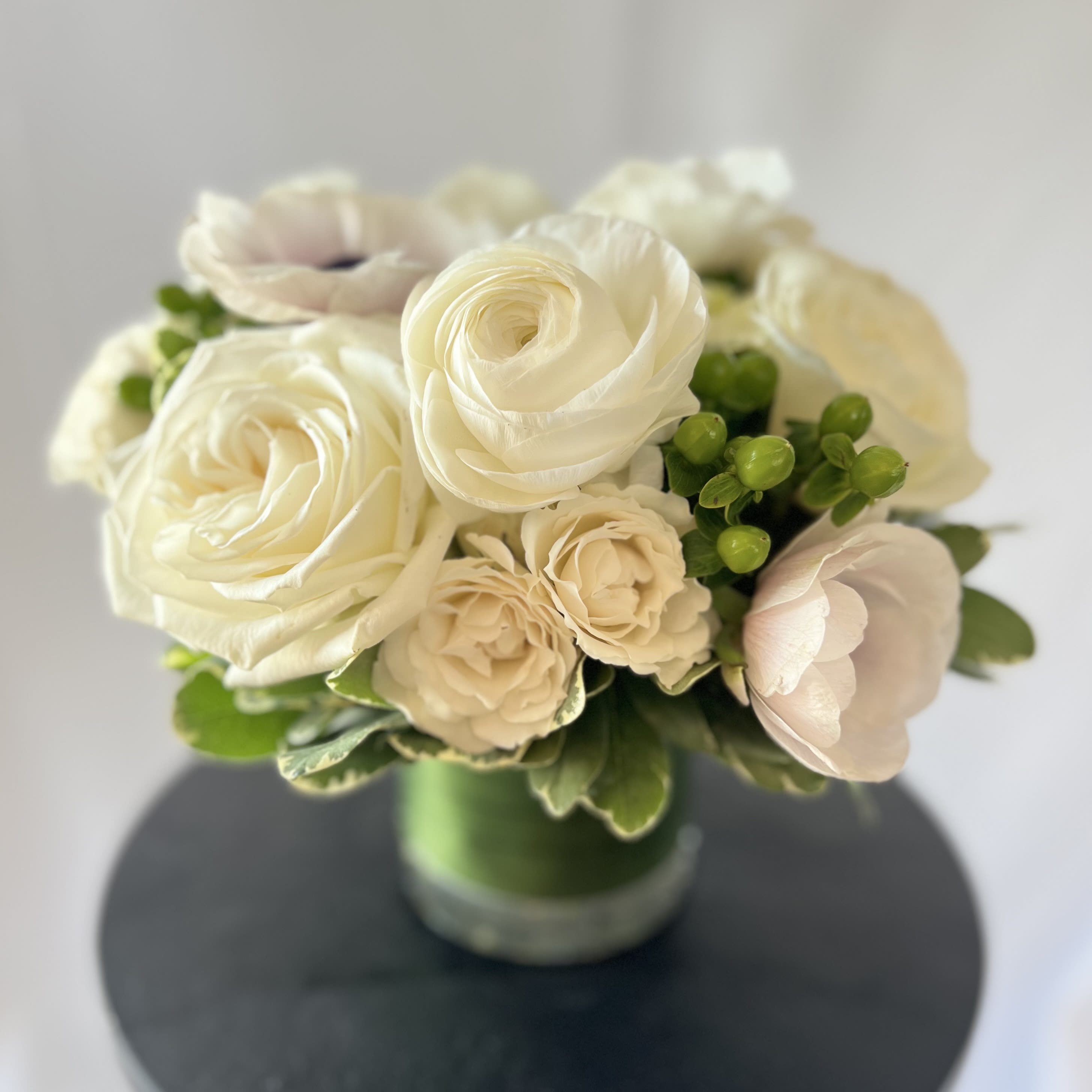 Pure White - Modern - Luxury Collection - A modern, hand tied compact styled arrangement of our white blooms from our weekly Studio Theme.   Specific flower varieties and colors pictured are not guaranteed. Each arrangement is delivered with a hand written card. 