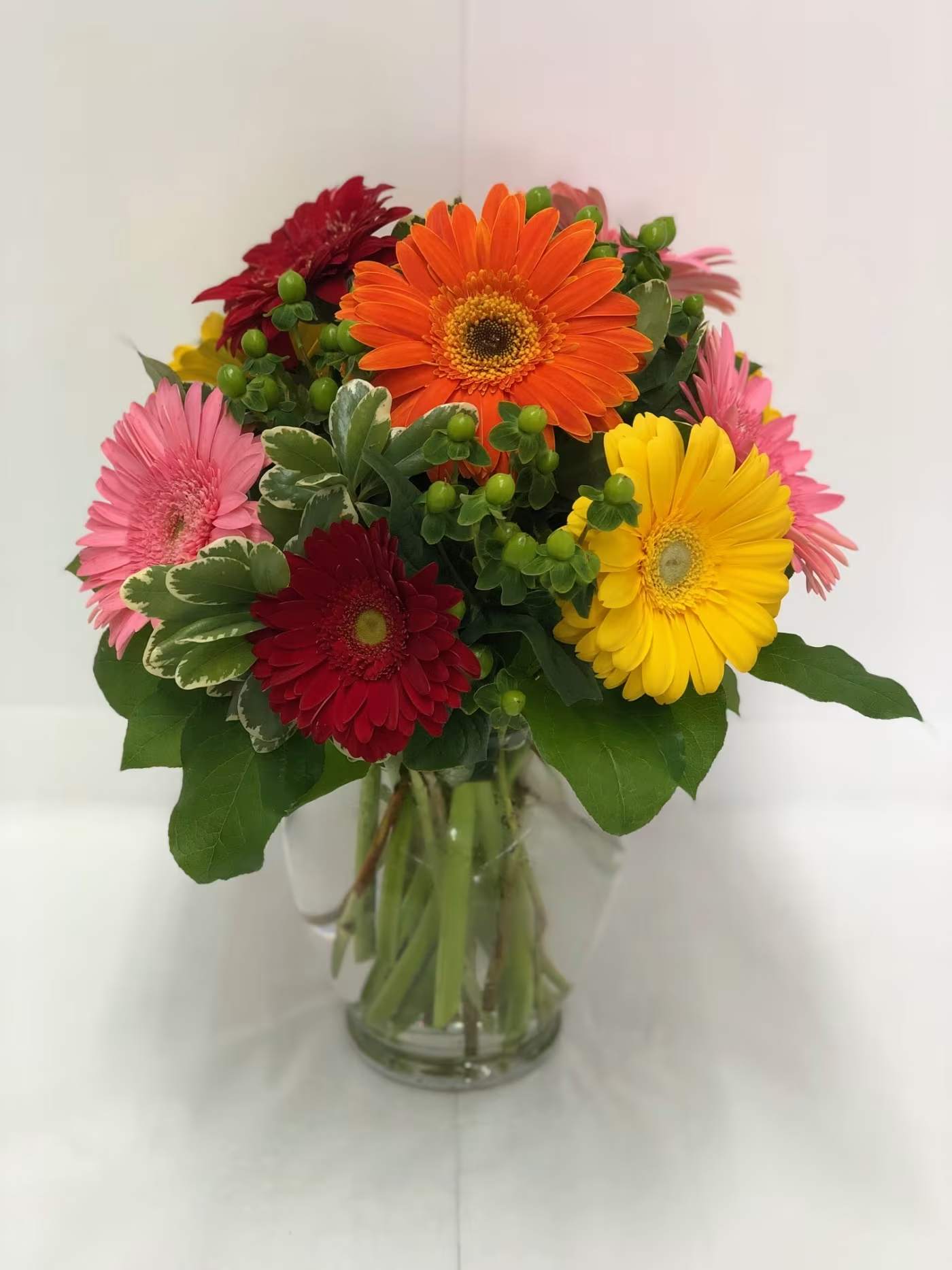 Gerbera Brights Vase Gerbera Brights Vase - Sending this bouquet just might be your brightest idea of the summer! Gerberas are so full of color charisma and charachter and this arrangement showcases their glory. A clear vase featuring a mixture of colored Gerberas, green hypericum berries and seasonal greenery is always sure to please.