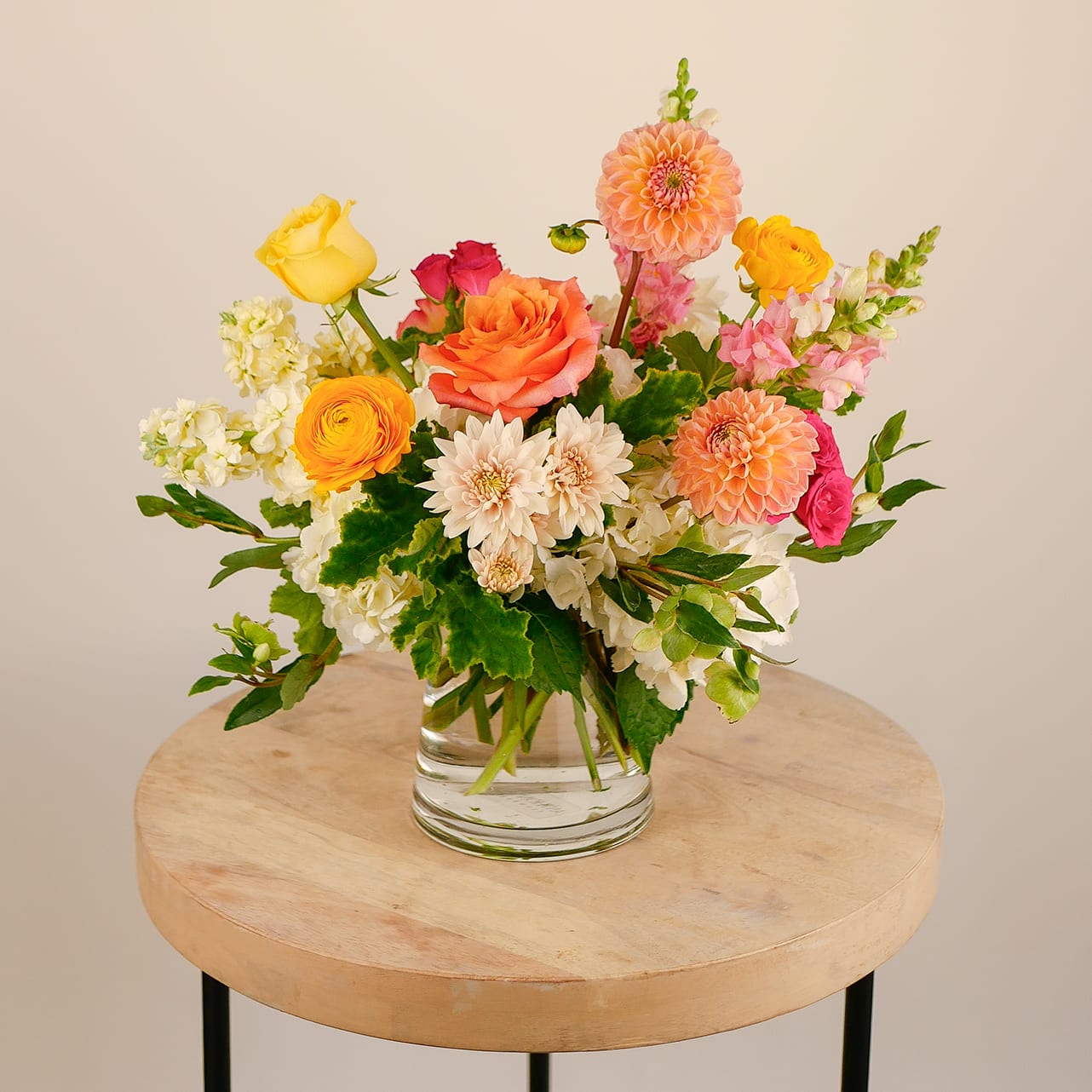 Color Me Happy - Bursting with bold personality, &quot;Color Me Happy&quot; is a joyful medley of bright dahlias, roses, ranunculus, and snapdragons arranged in a clean glass cylinder vase. This vibrant arrangement is perfect for celebrations, congratulations, or simply bringing sunshine into someone’s day. Lively, fresh, and full of energy—it’s happiness in floral form.