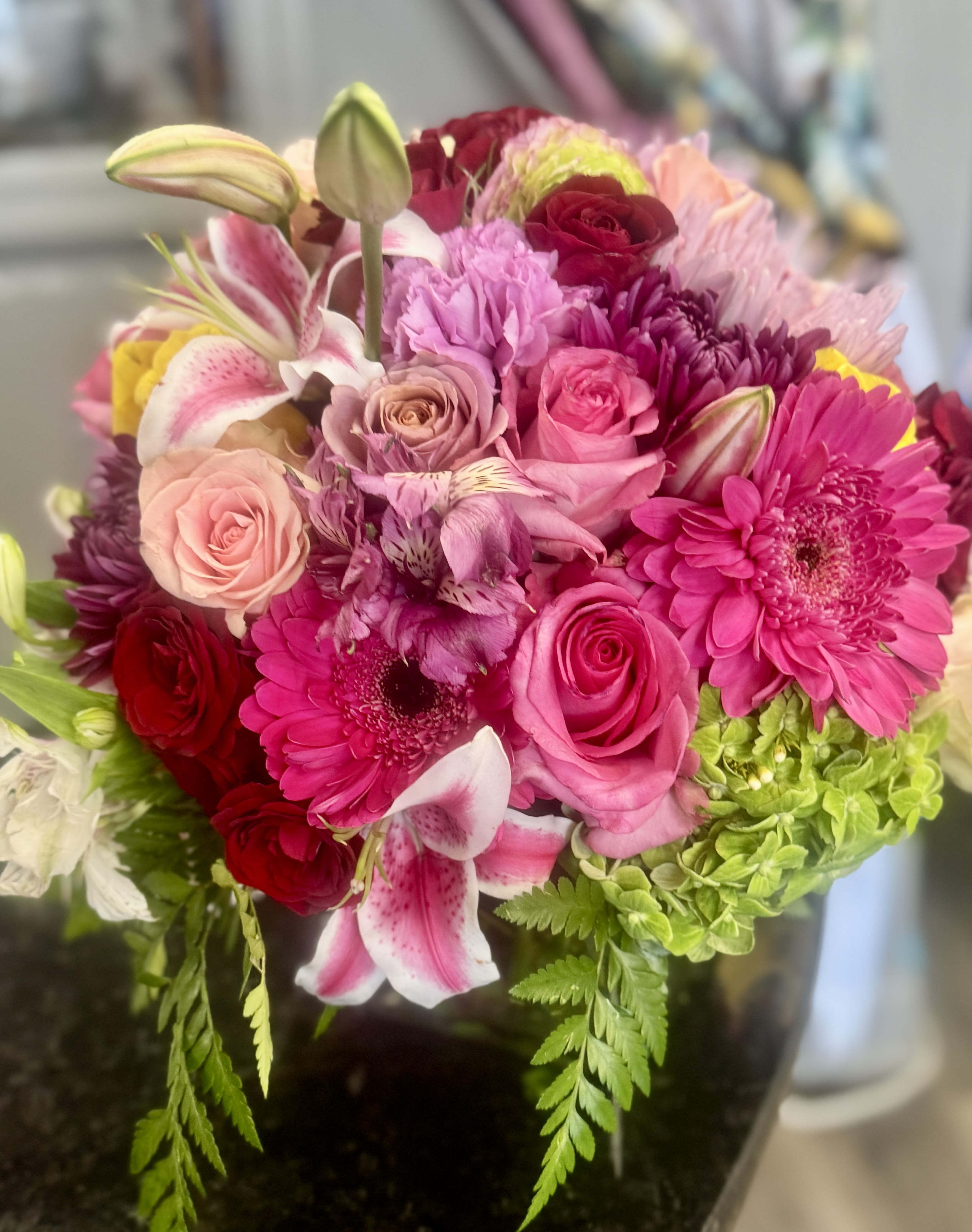 Pretty and Pink - A lower vase arrangement filled with greenery, an assortment of pink flowers and one hydrangea, white, green or pink. 
