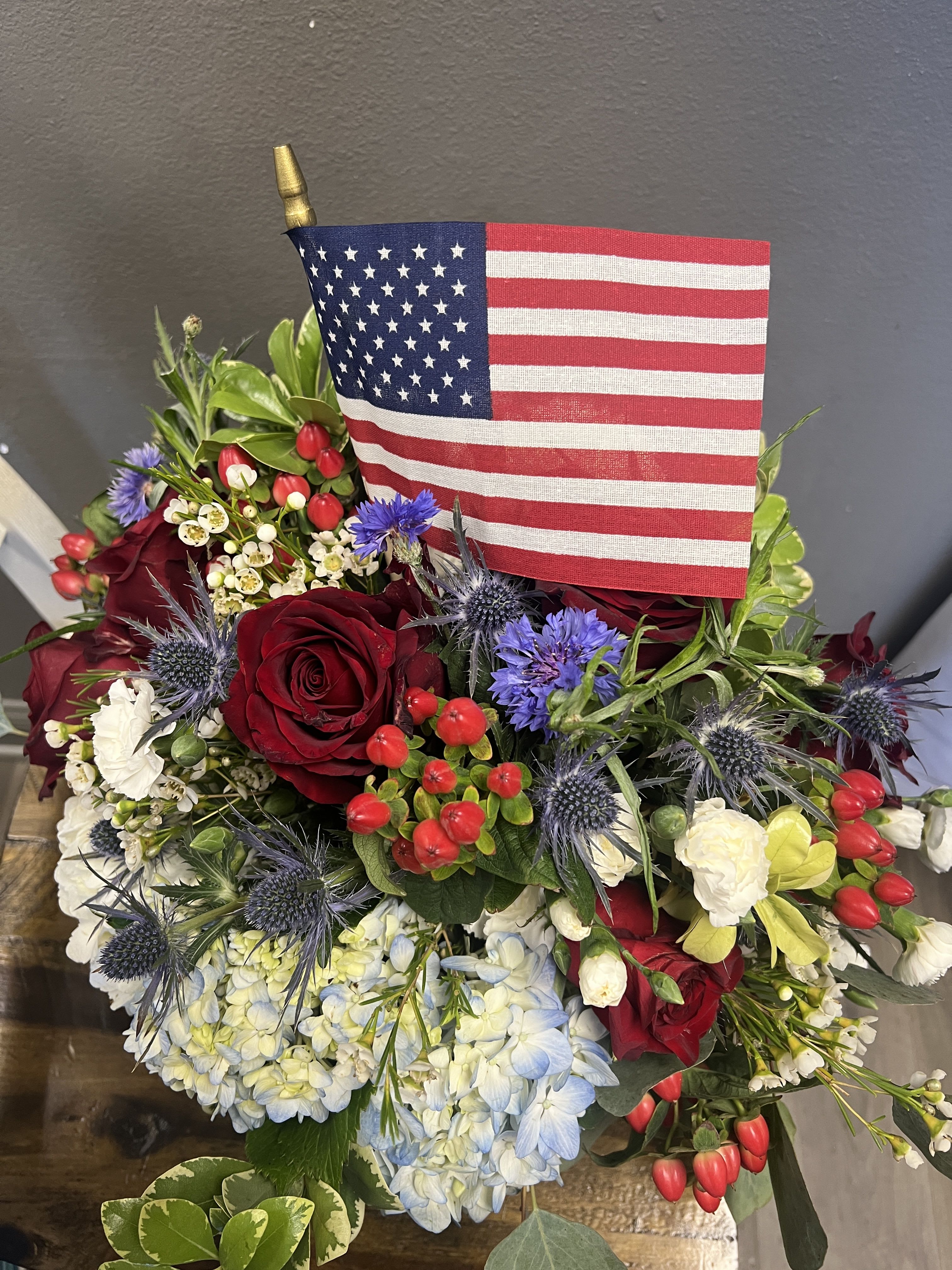 America The Beautiful - Red, white and blue flowers with an American Flag.  Celebrate our freedoms and send flowers!S