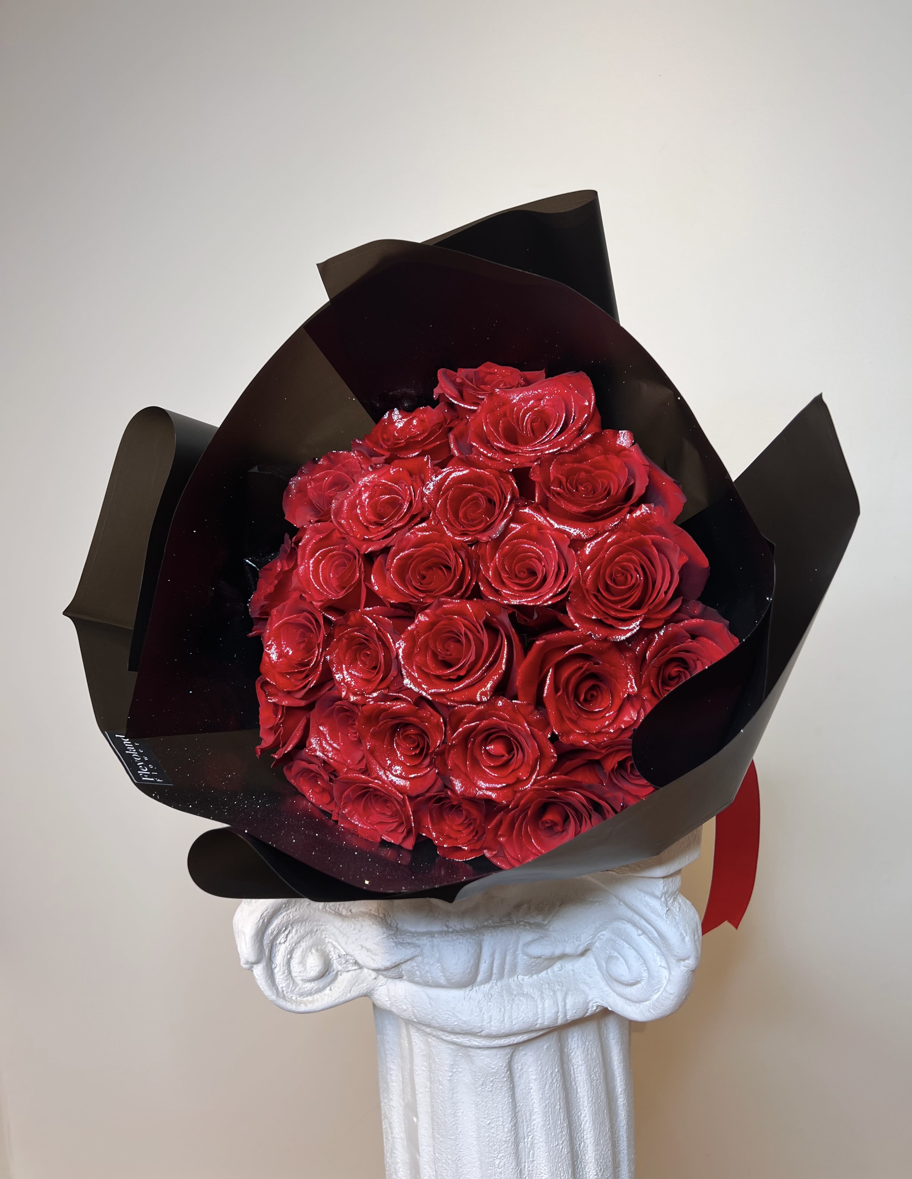 Glittered Red Bouquet - A bold and elegant design that speaks for itself. This bouquet features 24 fresh red roses, enhanced with a delicate touch of shimmering glitter to highlight the richness of every petal.  Wrapped in matte black paper and finished with a satin red ribbon, it’s the perfect choice for those looking to make a lasting, sophisticated impression. 