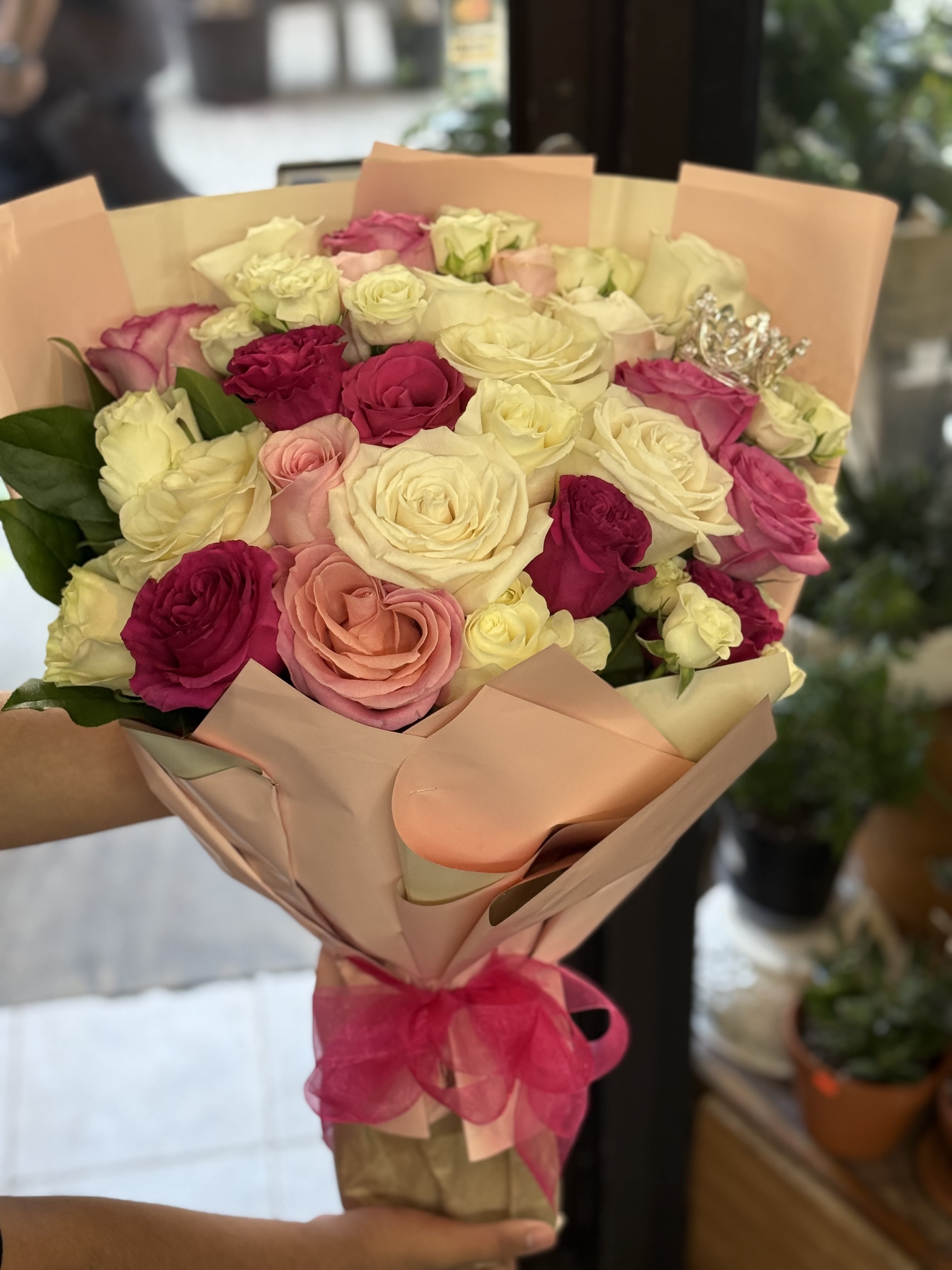 Rose Royale - This bouquet with soft blush, deep fuchsia, and creamy white roses paired with elegant wrapping and crown detail give it a regal, romantic vibe. Perfect for a princess moment or grand celebration. 