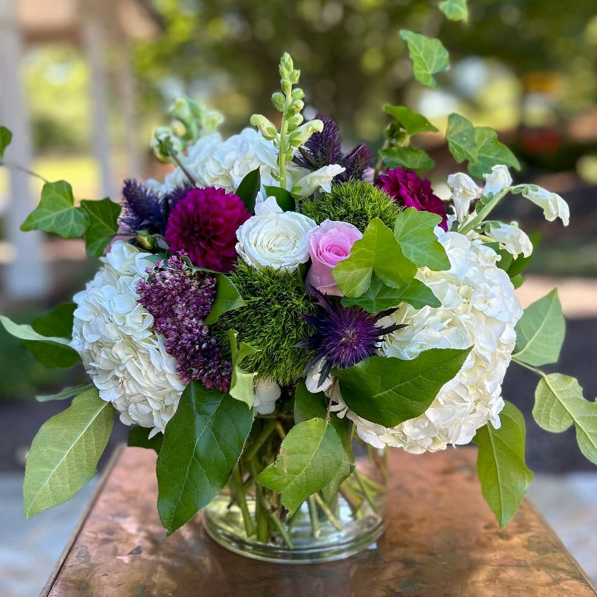 The Countryside The Countryside - The Countryside – Elegant Mixed Floral Arrangement | Wilmington, Delaware Local Florist Bring natural beauty and rustic charm indoors with The Countryside, a lush floral arrangement handcrafted by your trusted Wilmington, Delaware florist. This timeless design features fresh white hydrangea, soft light pink roses, classic white roses, elegant white snapdragons, and rich accents of dark pink and burgundy blooms. Artfully arranged in a clear glass cylinder vase, The Countryside captures the essence of a blooming country garden. Perfect for birthdays, anniversaries, sympathy, or just because. Available for same-day flower delivery in Wilmington, DE and surrounding areas. Choose our local flower shop for premium, fresh blooms and exceptional service.