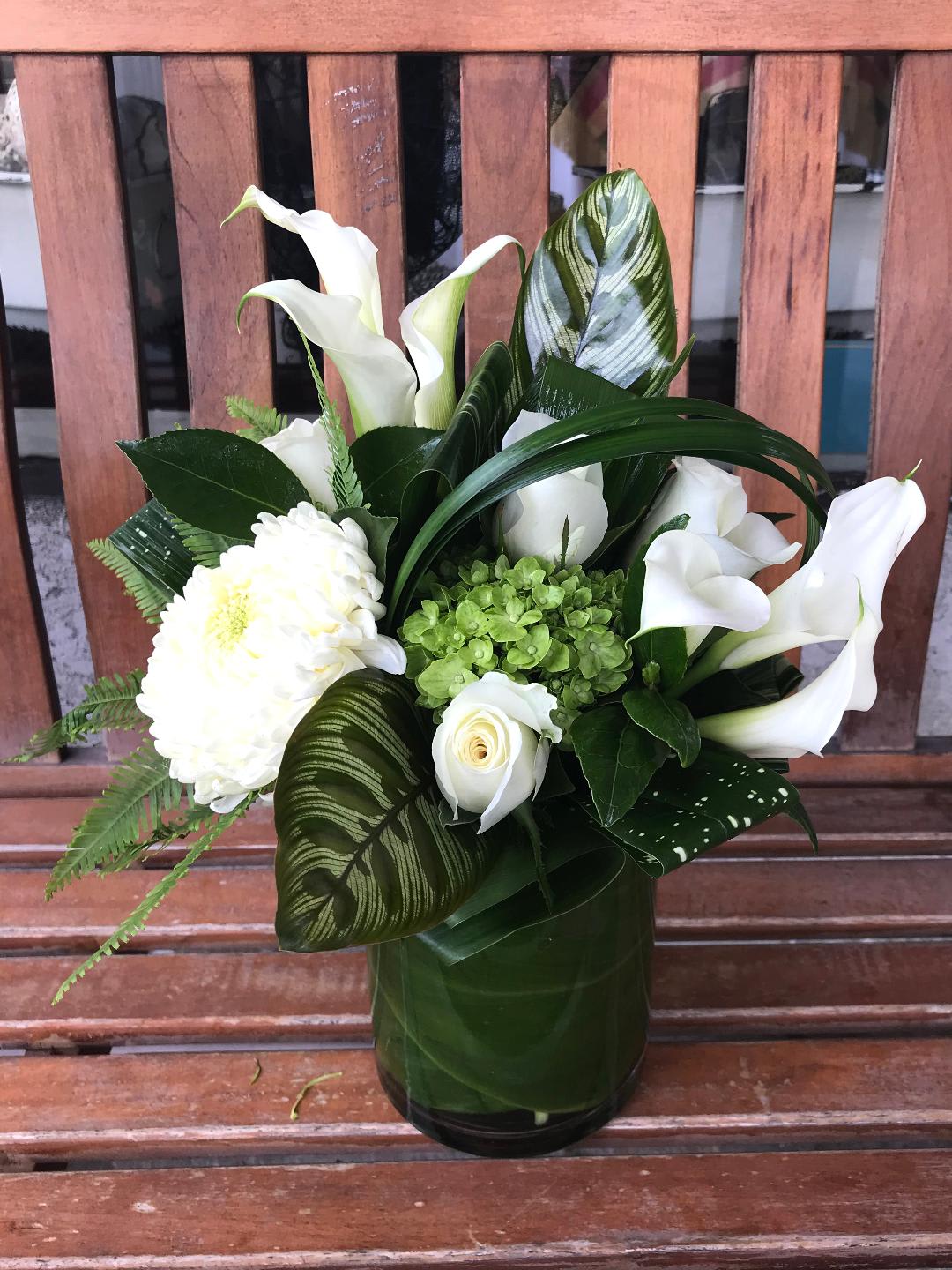 Blanco Co! - Modern, cube arrangement with a exquisite mix of white callas, green hydrangeas and white China's. Finished with a beautiful and striking assortment of tropical leaves. 
