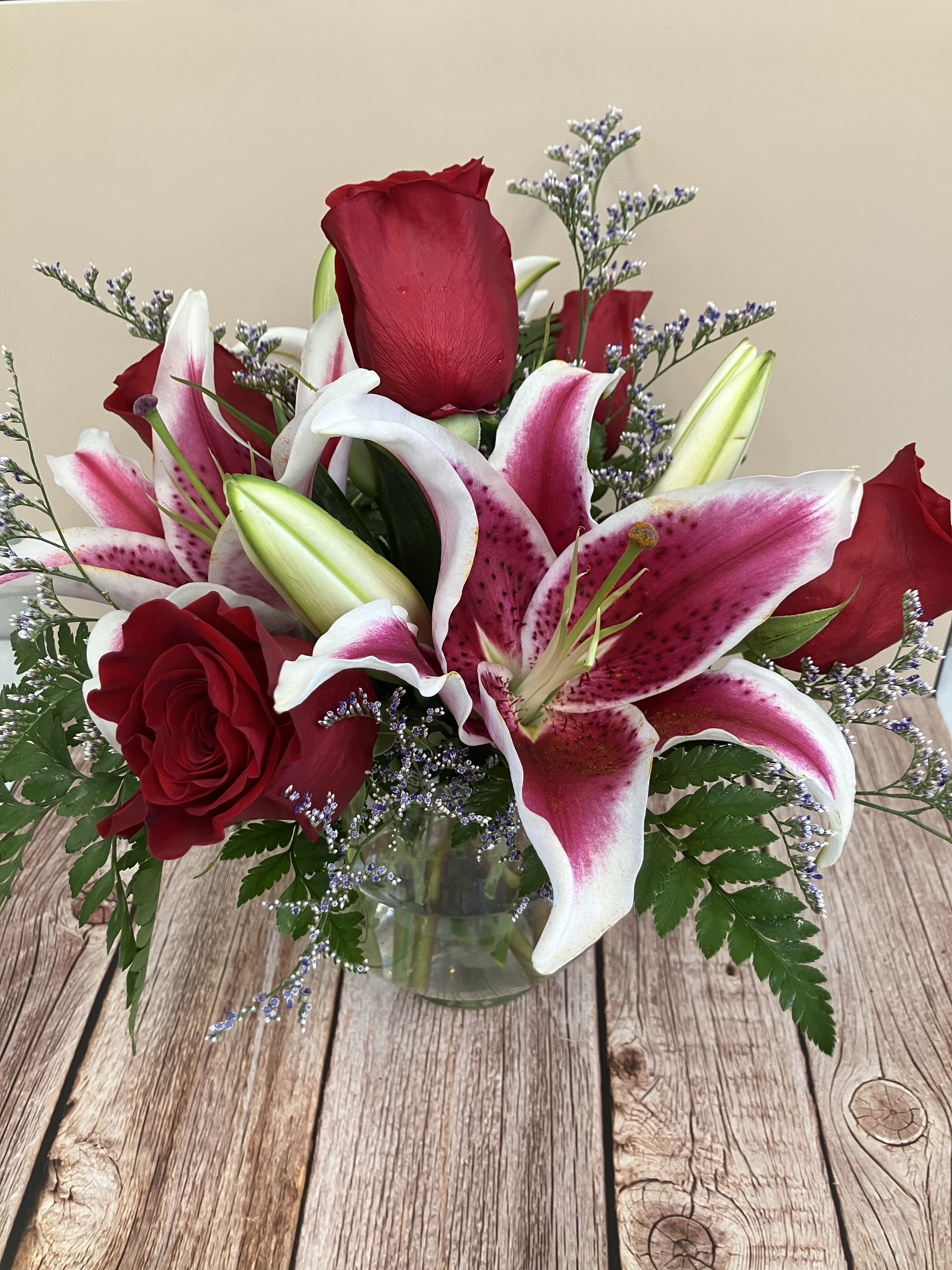 Luxury Roses and Lily - Send two of her/his favorite flowers arranged together in a round vase. Popular lily and red roses are stunning! Please note, designer will arrange as close to picture as possible! Includes 5 roses and two stems of lily plus fillers. Please note: It will not be the exact same arrangement every time, sometimes we have to make substitutions and do not want to make the arrangement unavailable because of a filler substitution. We make these as ordered with TLC! 