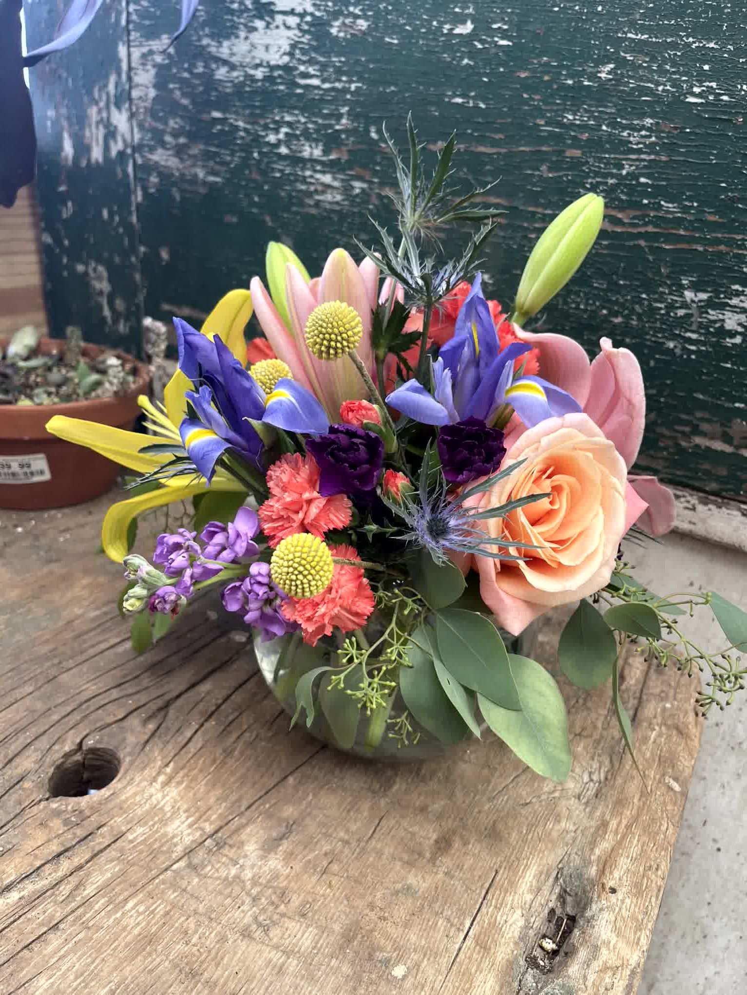 Bowl Of Beauty - Stunning roses, Lilies, Stock, Iris, Billy Balls, Thistle, and carnations make a dazzling impression! This burst of color is perfect to brighten anyone's day.