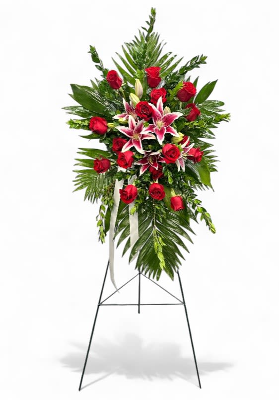 Starlit Remembrance Easel Starlit Remembrance Easel - The Starlit Remembrance Easel is a heartfelt floral tribute, featuring vibrant red roses that symbolize love and respect, beautifully complemented by stargazer lilies that evoke a sense of wonder and admiration. Situated among lush tree ferns, myrtle, and rich salal greenery, this arrangement creates a stunning display that captures the essence of a luminous farewell. The combination of these elements offers a harmonious blend of elegance and serenity, making it a fitting tribute to honor and remember a cherished loved one.