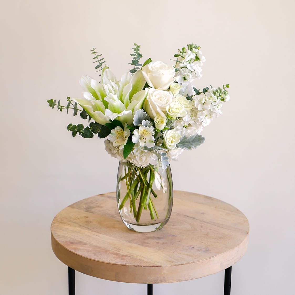 Pure Serenity - This graceful design features all white blooms such as roses, roselilies, fragrant stock, hydrangeas, alstroemeria and more in a medium glass vase. Arrangement approximately measures 15 inches tall.