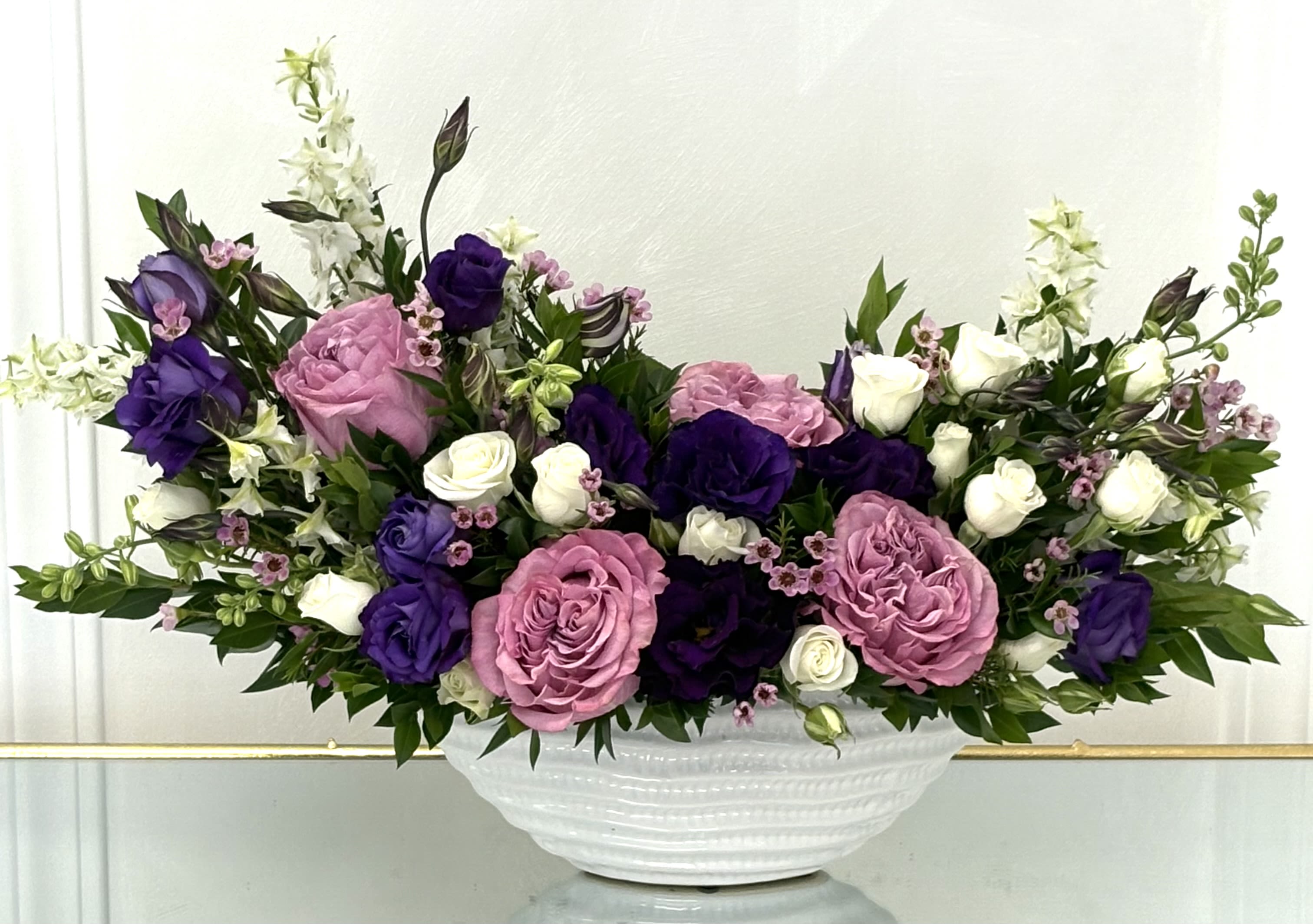 Purple Reverie By VLM Flowers - Lose yourself in a poetic blend of color and grace with Purple Reverie. This lush arrangement pairs rich purples, soft pinks, and ivory blooms in a flowing, organic shape. It’s designed to evoke peace, reflection, and gentle charm—ideal for memorial settings, thoughtful gifts, or elegant home decor.