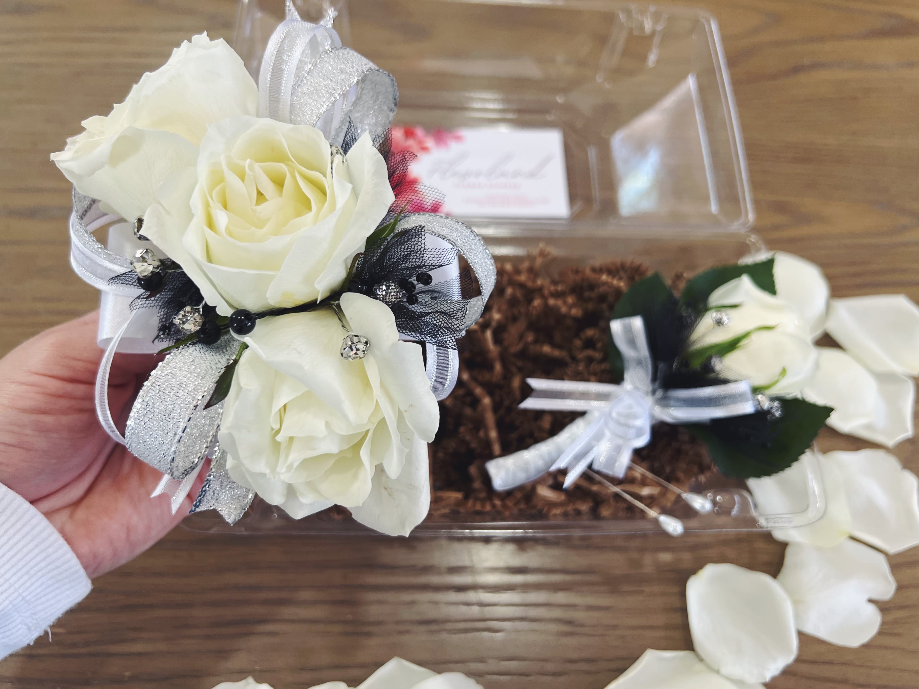 White Rose Corsage and boutonnière  - This white corsage with silver and black accents, paired with its matching boutonnière, is the perfect combination for a classic and elegant look. The soft white tones, enhanced by the silver shimmer and black contrast, add a touch of distinction, making it ideal for special events.  A floral detail that exudes sophistication and style