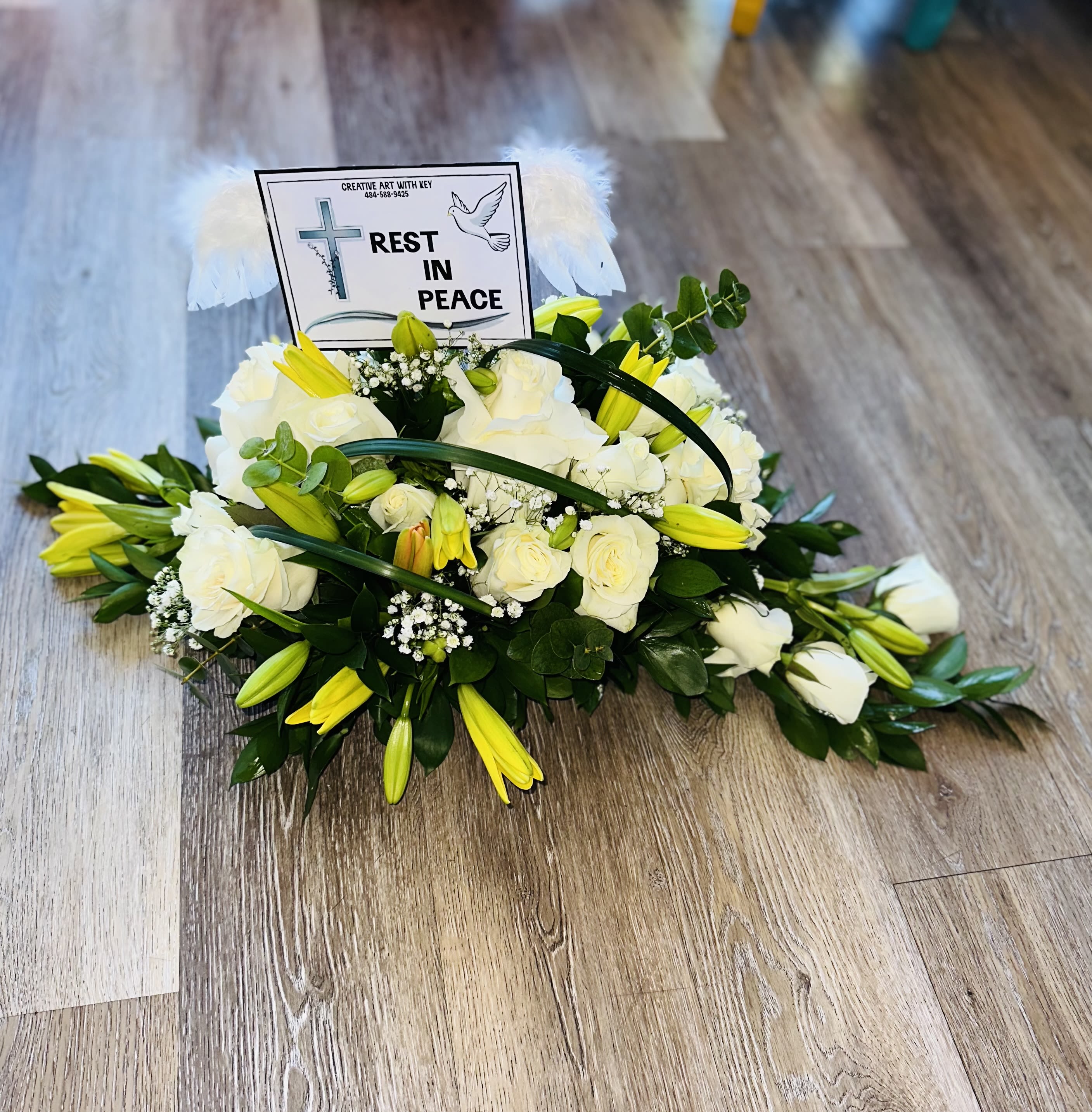 FUNERAL CASKET - FUNERAL CASKET, VARIETY OF ROSES, CARNATIONS, RUSCUS, LILIES, PERSONALIZED AND LAMINATED CARD WITH ANGEL WINGS