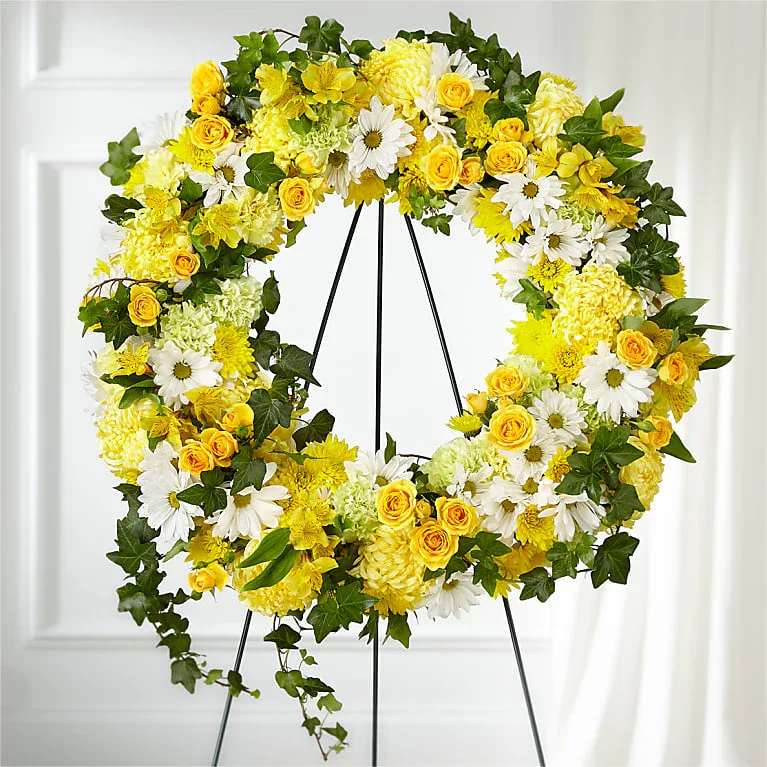 Golden Remembrance Wreath - Whether yellow was their favorite color or it captures the essence of their radiance, a ring of bright blooms thoughtfully displays your sentiment. Our Golden Remembrance Wreath is composed of spray roses, daisy pompons, carnations and more. Each flower is selected to beautifully accent one another and the love you are sending.