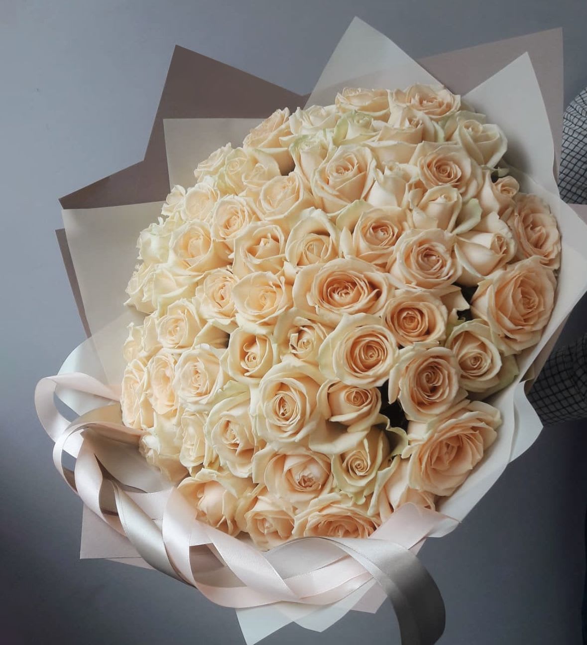 50 Creamy roses - A stunning bouquet of fresh light peach roses, perfect for any occasion. Wrapped in matte film and tied with a ribbon. This elegant arrangement is sure to impress. Delivered in an aqua box for ultimate freshness.