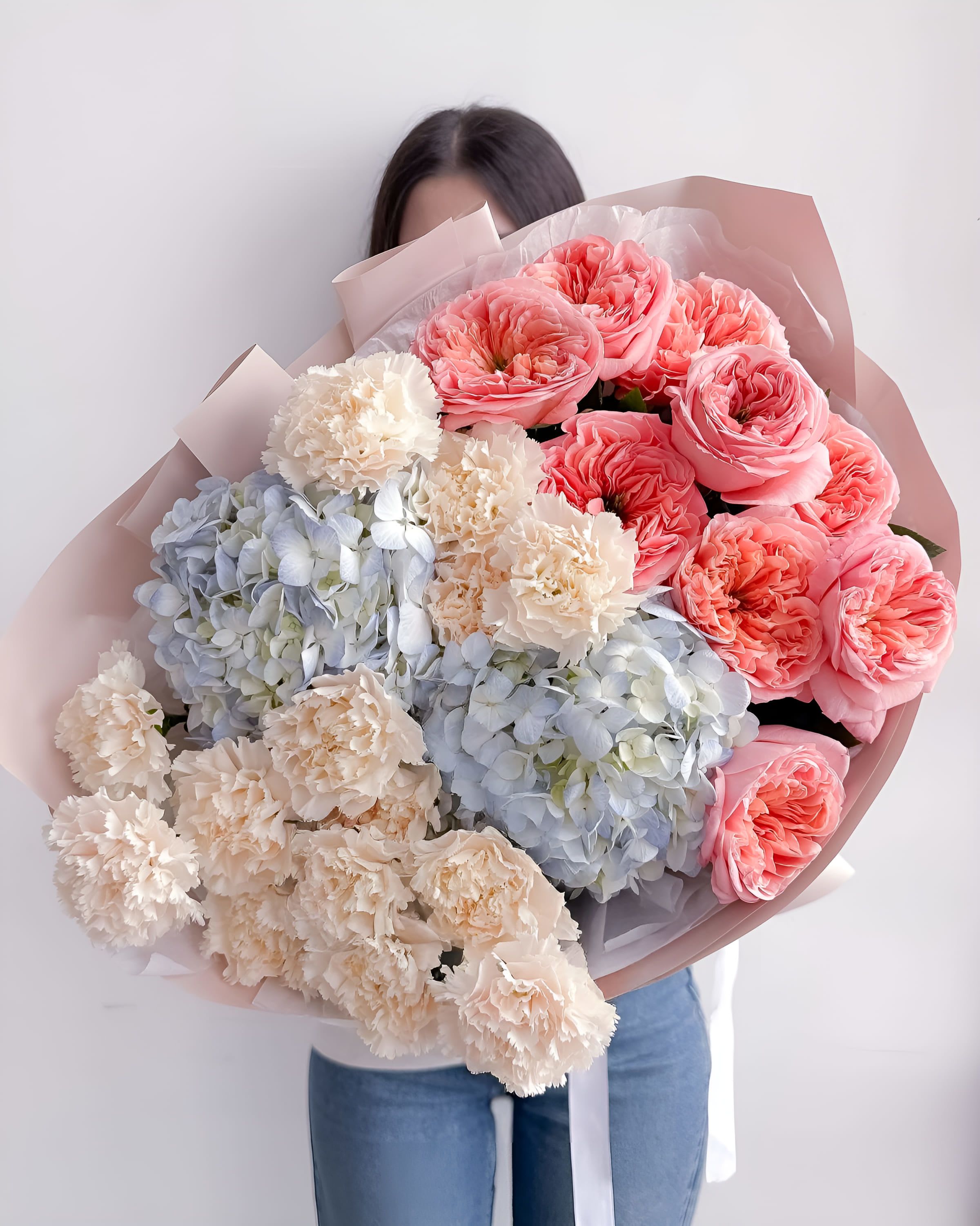 Coral Clouds - A cheerful blend of coral garden roses, soft cream carnations, and powder blue hydrangeas. Coral Clouds radiates warmth and calm with its contrast of vibrant and pastel tones — ideal for expressing gratitude, celebrating a milestone, or bringing joy to someone’s day.