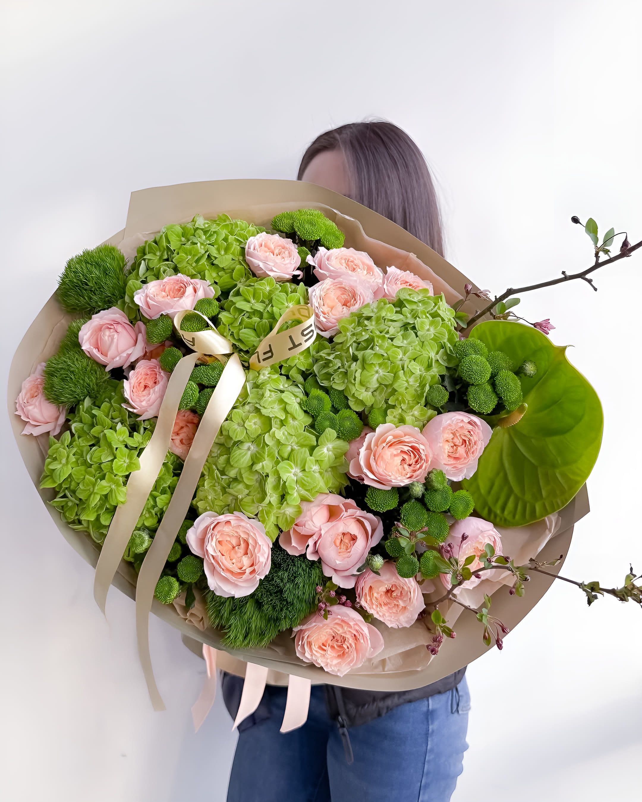 Garden Whisper - A lush and refreshing bouquet featuring soft peach garden roses, vibrant green hydrangeas, and playful green button chrysanthemums. Accented with blooming branches and exotic anthurium, Garden Whisper brings together serenity and sophistication in perfect harmony. Ideal for birthdays, celebrations, or simply to brighten someone’s day with the energy of spring.  Size on the photo: Deluxe
