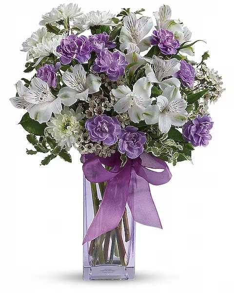 Teleflora's Lavender Laughter Bouquet - Fill her heart with laughter! The ultimate lavender-lover's bouquet, this gleeful gift of white and lavender blooms is delivered in a pretty pale lavender vase she'll cherish forever. Lavender organza ribbon adds that gifting touch.  Includes white alstroemeria, miniature lavender carnations, white chrysanthemums and waxflower, accented with fresh pittosporum and lemon leaf. Delivered in a Bunch vase.