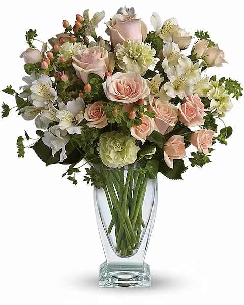 Anything for You by Teleflora - You'd do anything for her, so let her know how you feel by sending this generous and gorgeous arrangement. Who could ask for anything more?  Beautiful peach roses and spray roses, white alstroemeria, brilliant green carnations, peach hypericum and fresh garden greens are perfectly hand-arranged in a feminine Couture Vase.