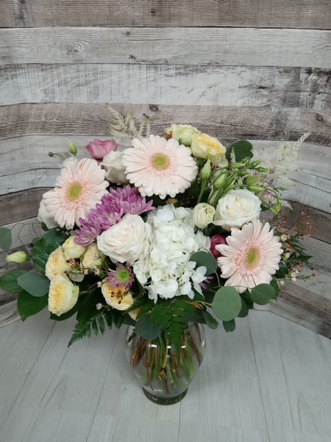 Sand Castle  - Bring the charm of the shoreline indoors with Sand Castel, a serene and sun-kissed floral arrangement inspired by ocean breezes and warm, sandy days. Soft, neutral-toned blooms like creamy roses, pale peach gerbs, and delicate lisianthus mingle with textural grasses and hints of sea-hued eucalyptus. The composition evokes a weathered elegance—perfect for coastal or beach-themed events, or anyone who longs for the tranquil beauty of the seaside. A gentle escape, petal by petal.