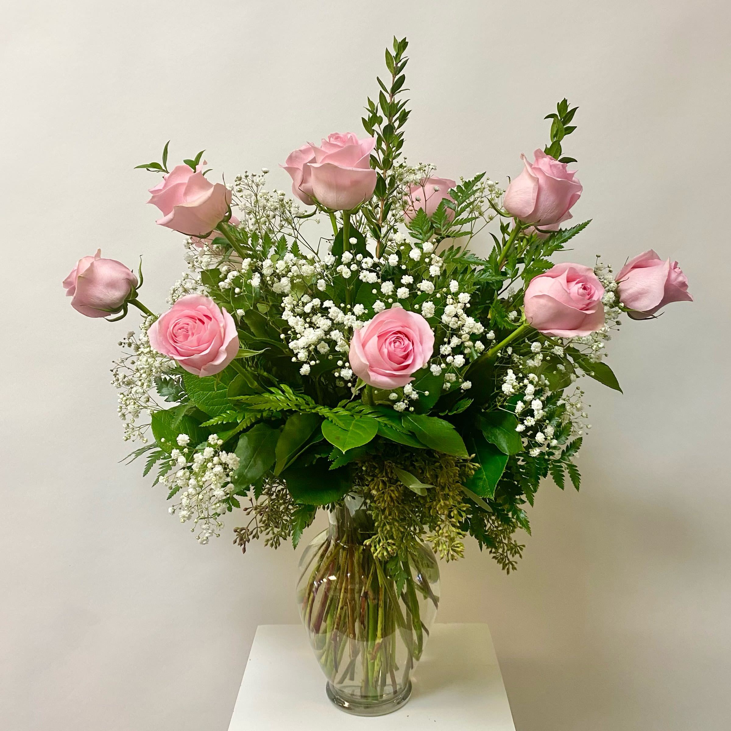 Classic Light Pink Dozen - Light Pink Dozen Roses with W/ Filler in a Glass Vase. Filler Flowers will be either Babies Breath or Wax flowers.  Write in the Special Instructions if you have a preference Babies Breath or Wax Flower.