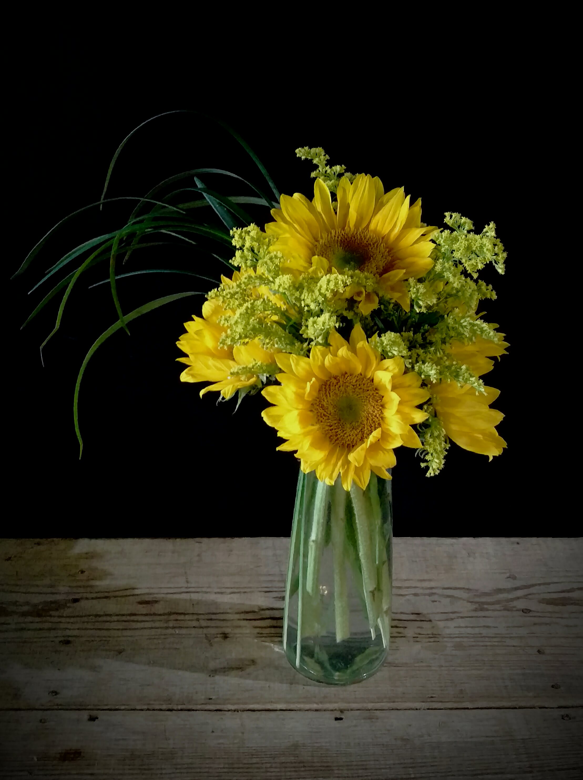 Sunshine Daydream Sunshine Daydream - The Sunshine Daydream Bouquet highlights stunning sunflowers to capture their every attention with its bright beauty. Gorgeous sunflowers are accented with solidago, lily grass blades and lush greens to create a memorable flower bouquet. Presented in a clear glass tapered square vase, this arrangement sends your warmest wishes and highest hopes for the days ahead.