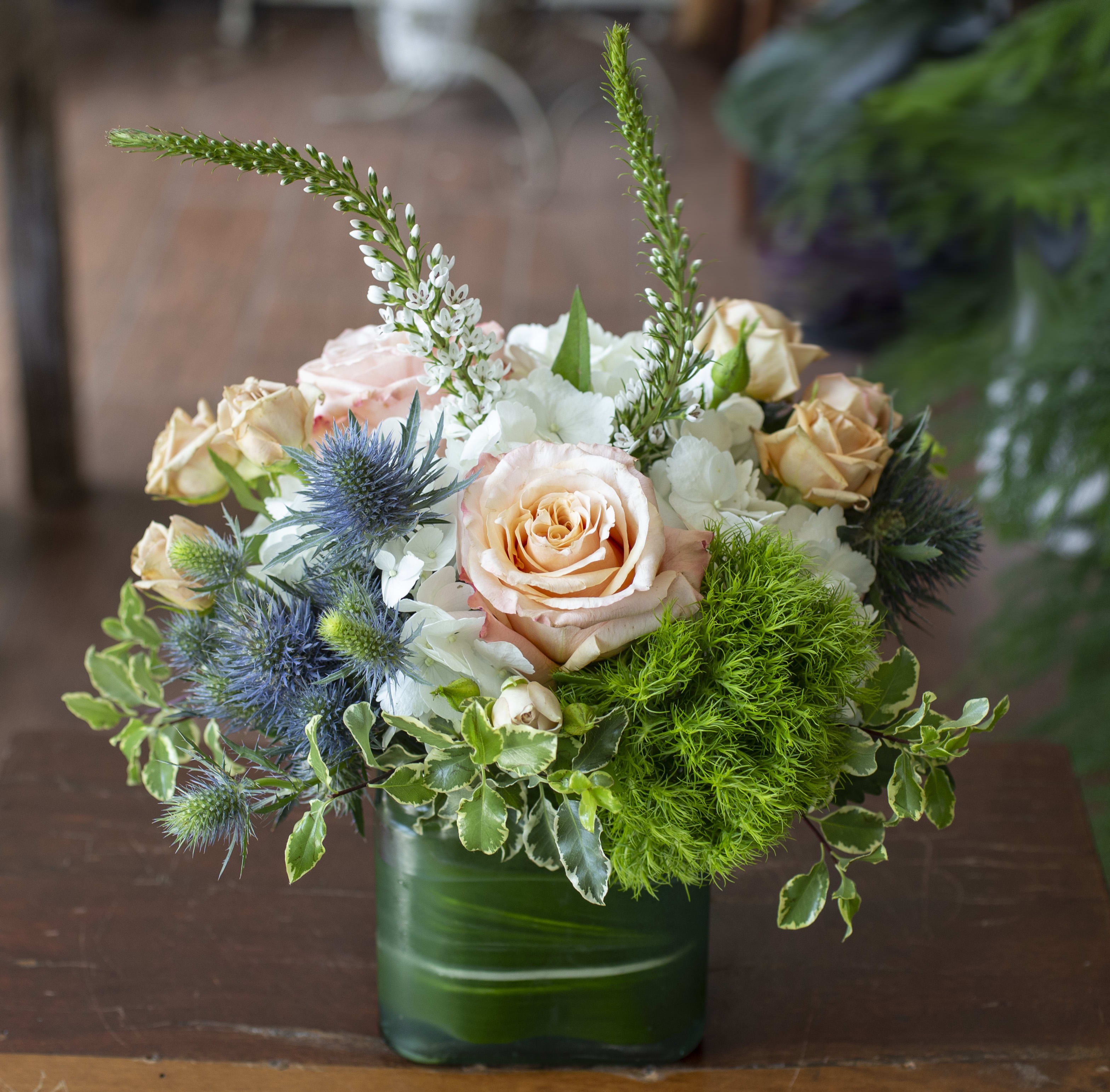 Phoenix - Earthy flowers arranged in a glass vase with leaf.