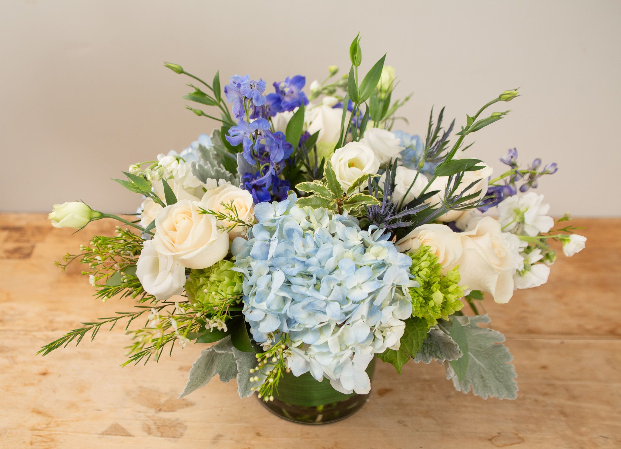 Cape Favorite  - Inspired by the blues and creams in the classic toile print, this arrangement includes blue hydrangea, ivory roses and other special blooms for a fresh design. $200 size is shown. Approx 16x16