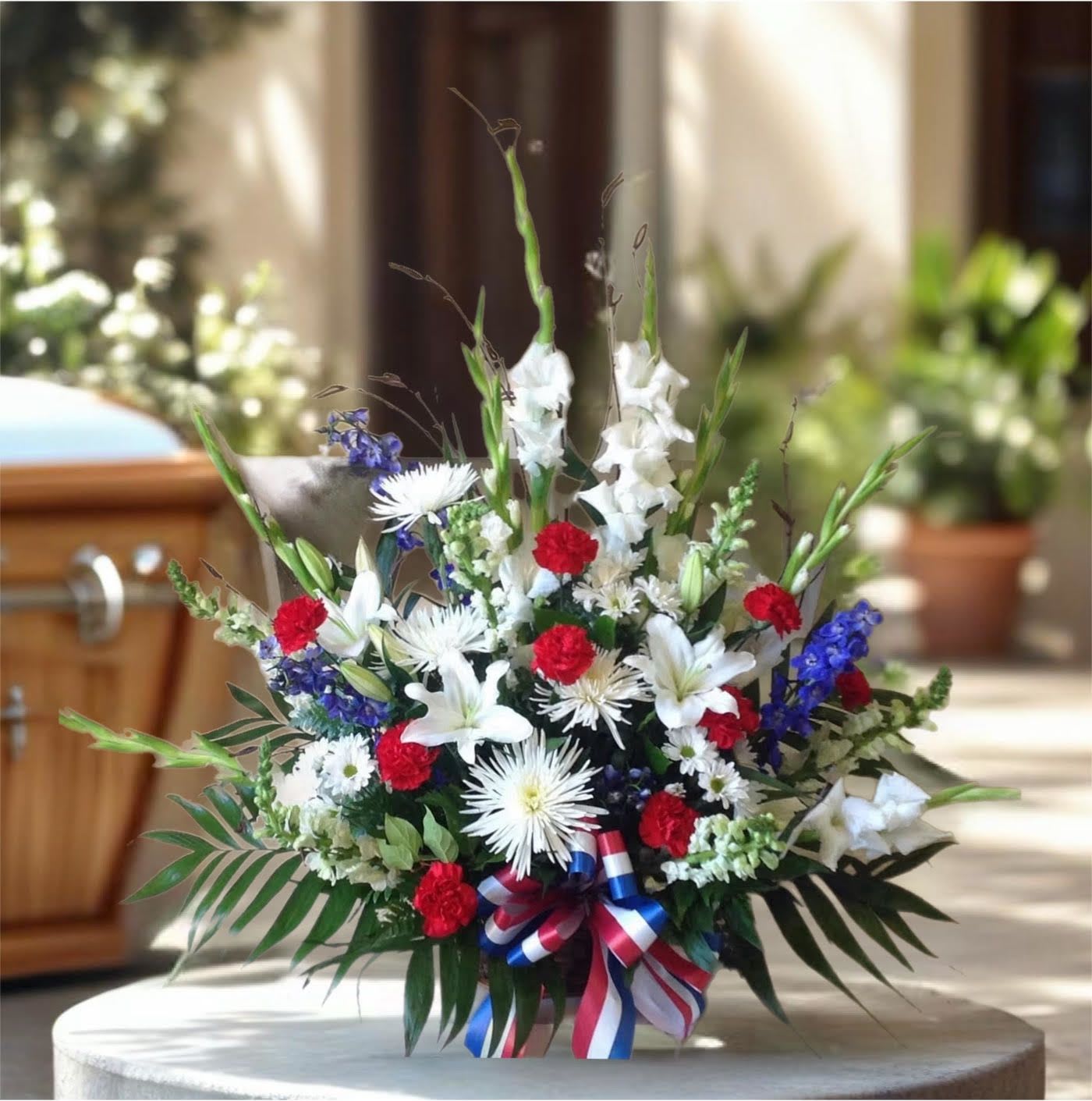 American Pride Arrangement American Pride Arrangement - A beautiful mix of all-American red, white and blue flowers such as roses, lillies, carnations, gladiolus, snapdragons, blue delphinium mums and more are perfectly arranged in a wicker basket.