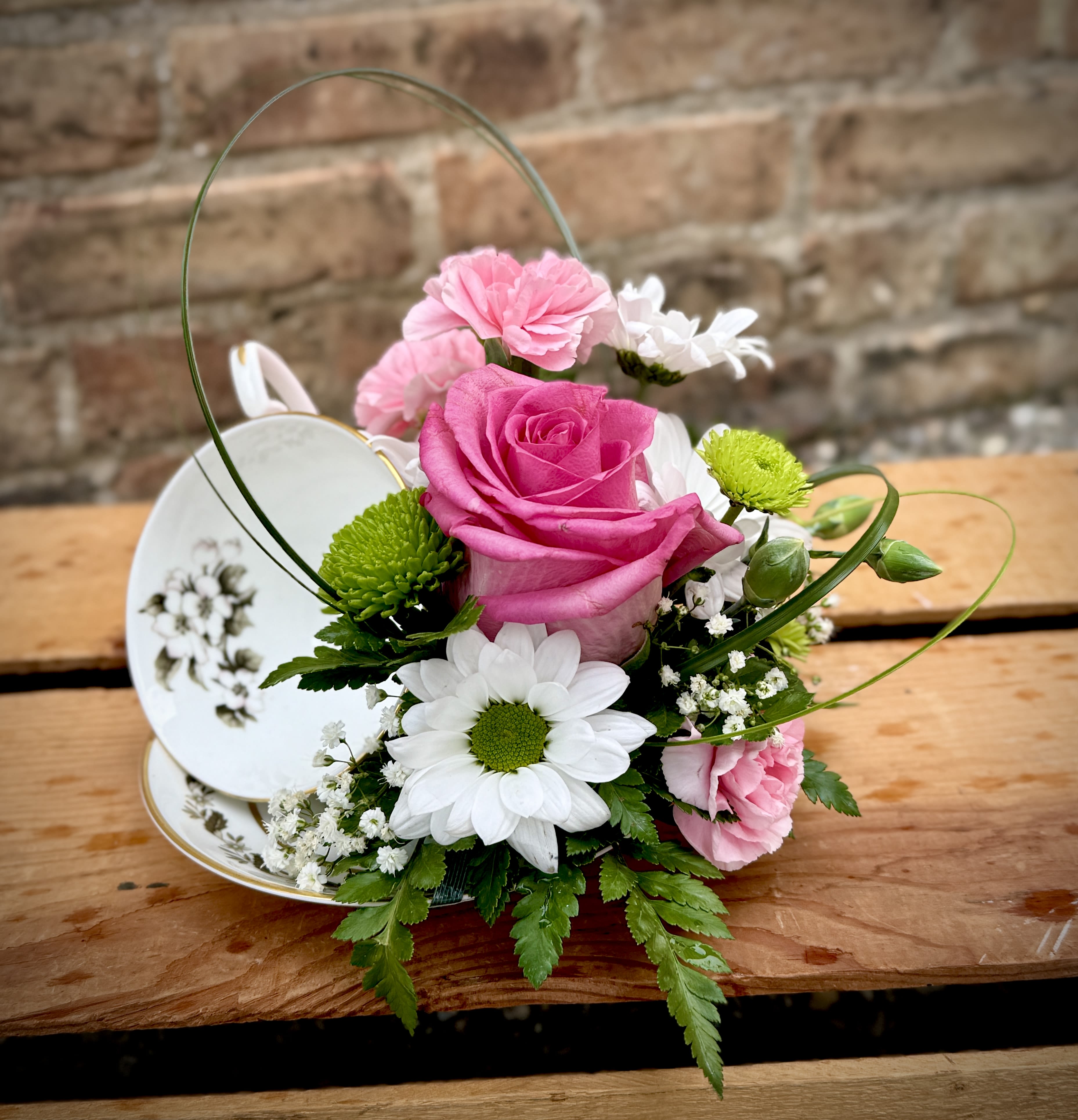 Teacup Garden - A beautiful vintage cup and saucer with a lovely fresh arrangement. The arrangement sits next to this beautiful cup. A perfect gift in a gift!  We are proud to deliver our flower creations to the Kenosha, Somers, and Pleasant Prairie areas. With over 55 years of combined flower design experience in Kenosha, Wisconsin, A Summer's Garden Florist and Gifts is the perfect choice for the freshest flowers, most creative design, and exceptional customer service.
