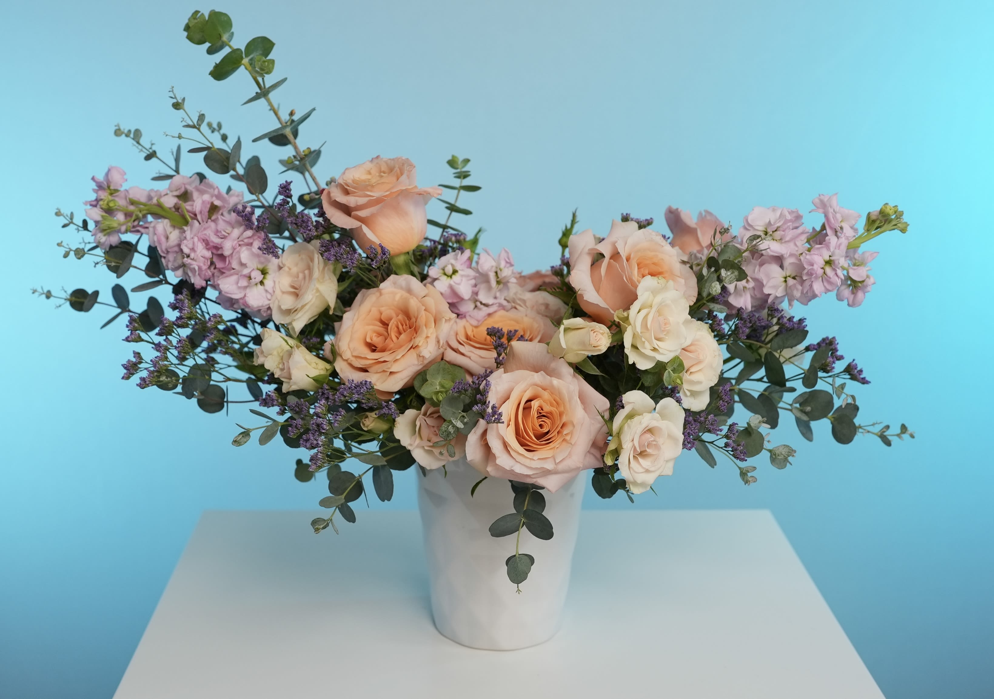 Peach Serenade Peach Serenade - Delicate yet full of character, Peach Serenade brings together the understated elegance of peach garden roses, creamy spray roses, and soft lavender stock in a graceful, airy composition. Hints of purple statice and eucalyptus foliage add natural movement and contrast, creating a bouquet that feels both timeless and refreshingly modern. Each bloom is carefully selected for its subtle charm and captivating scent—notes of soft tea rose, warm vanilla, and clean herbal undertones blend into a soothing floral symphony. Perfect for birthdays, anniversaries, baby showers, or simply brightening someone’s day. Style: Romantic, garden-inspired, modern-classic Scent: Softly floral with warm and clean herbal notes