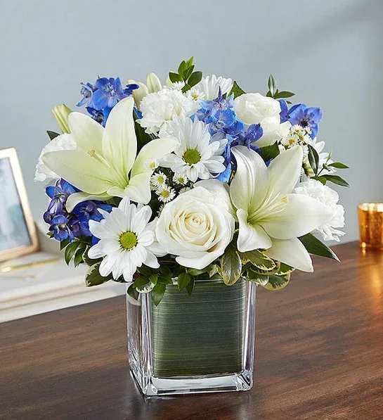 Skies Of Remembrance - Vase arrangement with Lilys, Carnations, Daisy Poms, Delphinium, Roses And Monte Casino with lush Greenery.