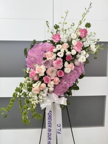 Sympathy Funeral Floral Heart - Express your deepest sympathy with our an artful statement piece. Our large heart structure floral design display on an easel. Personalized with a custom ribbon message.  Fresh premium floral design includes a composition of carnation, Ecuadorian roses, lisianthus, stock, bells, dendrobium orchids, and lemon leaves.   Floral colors can be customized upon request.  ***Subject to substitutions based on seasonal or overall availability.***  Florist reserves the right to replace certain flowers in an arrangement with different ones if the one on the photo display is not available. Florist will strive to replace with alternatives that maintain the arrangement's original style, color palette, and overall aesthetic. Utilizing florals of  equal or greater value.