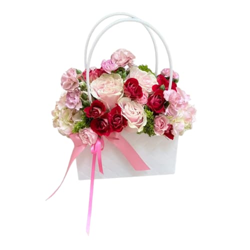 The It Bag - Make a statement with &quot;The It Bag,&quot; a modern and chic floral arrangement that's as stylish as it is unforgettable.  Lush hydrangeas and a mix of red and pink roses, accented by the subtle green of dianthus, are artfully arranged within a stylish white handbag, creating a captivating and eye-catching design.