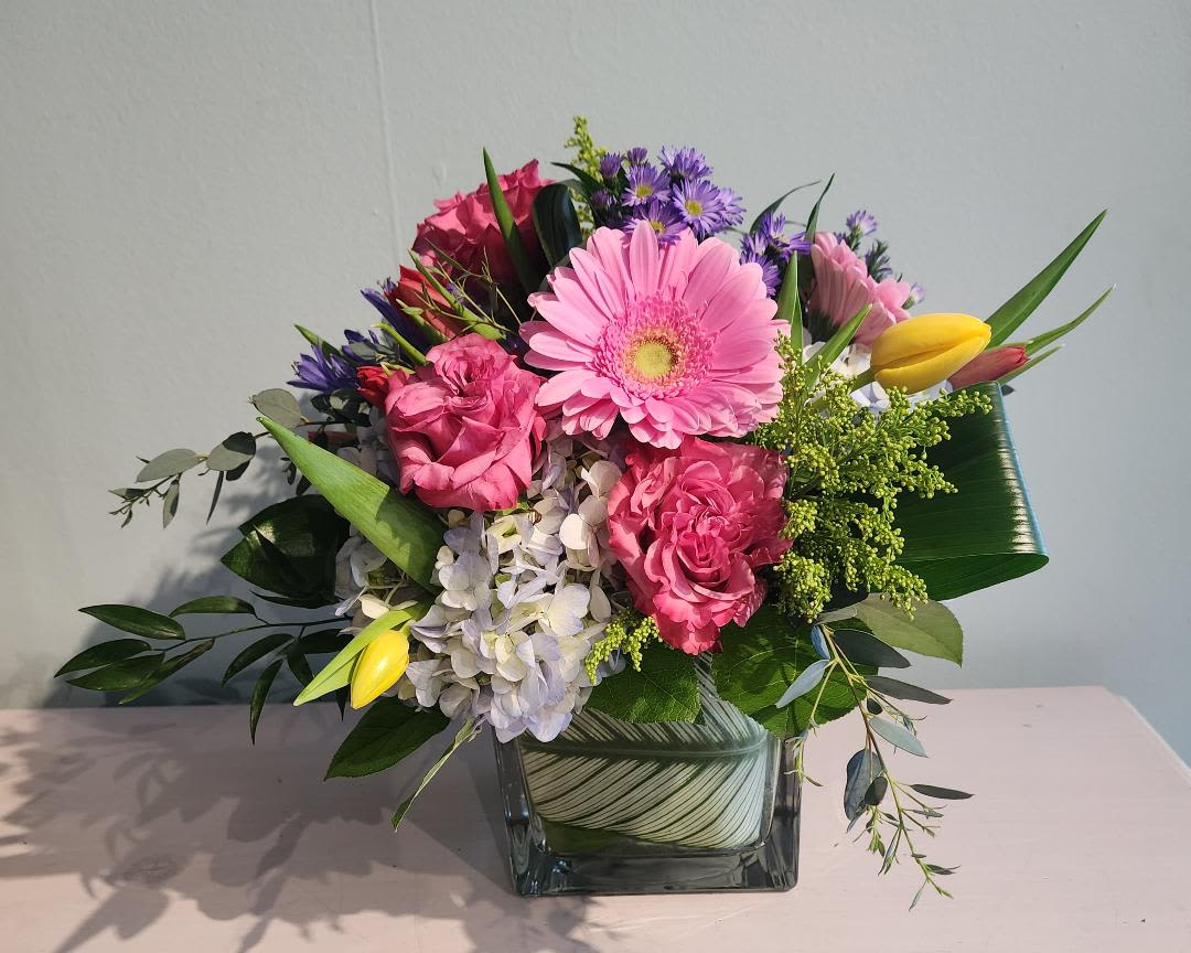 Summer Love Summer Love - Gorgeous spring blooms arranged in a large glass cube vase overflowing with hydrangeas, hot pink garden style roses, gerbera daisies, tulips and accents of other flowers and fresh greens. Definitely makes a statement!! Tulips will be substituted during summer months.
