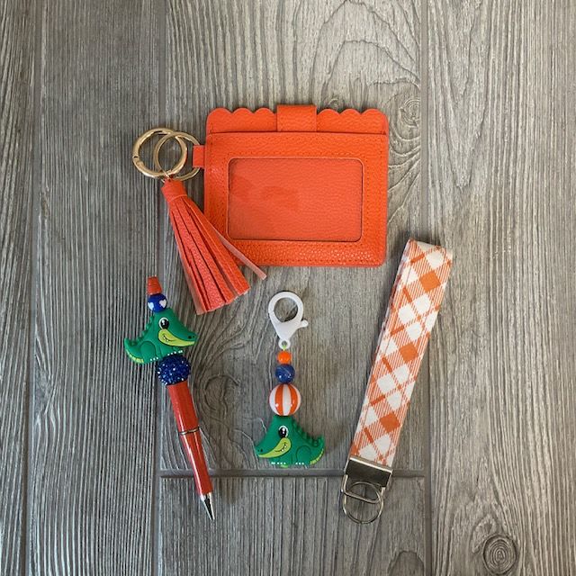 Orange Gator Gift Set - Included in Orange Gator Gift Set -1 Gator Pen (Style May Vary) -1 Gator Keychain (Style May Vary) -1 Orange Wristlet -1 Orange Wallet