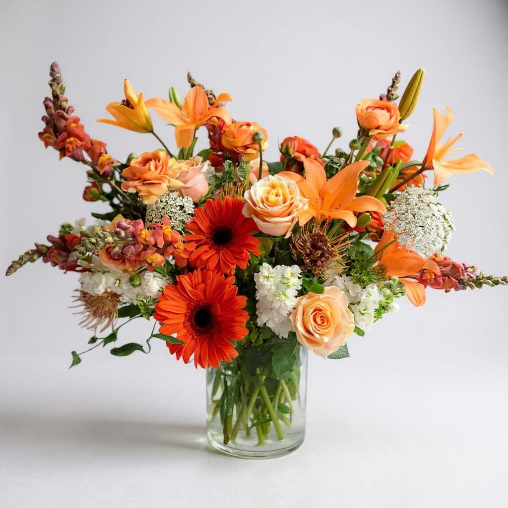 Awesomeness Bouquet - &quot;Awesomeness&quot; is a burst of warmth and vibrancy captured in a vase! Immerse yourself in the lively hues of orange gerbera daisies, their cheerful petals radiating joy and energy. Towering snapdragons stand proudly alongside the striking orange lilies, their exotic beauty enhancing the overall allure. The unique pin cushion protea introduces a touch of the extraordinary, its fascinating texture making a bold statement. To add a touch of softness and depth, wispy filler delicately weaves through the arrangement, creating an ethereal dance. Finally, the bouquet is crowned with the subtle elegance of peach roses, completing this symphony of colors and textures. &quot;Awesomeness&quot; is more than just a floral arrangement; it's a celebration of life, vibrancy, and the joy that blooms bring. Gift this burst of awesomeness to brighten someone's day or to add a lively touch to your space.
